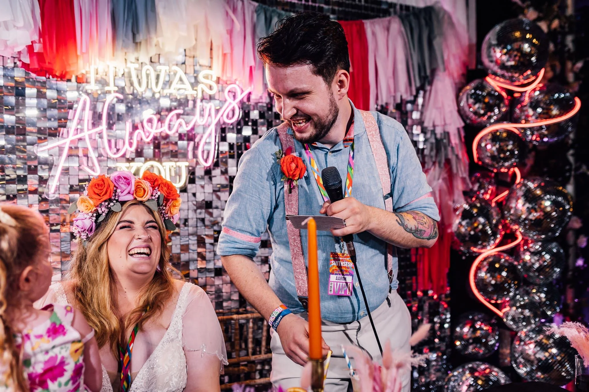 Aaron speaking into a microphone as Chloe laughs beside him