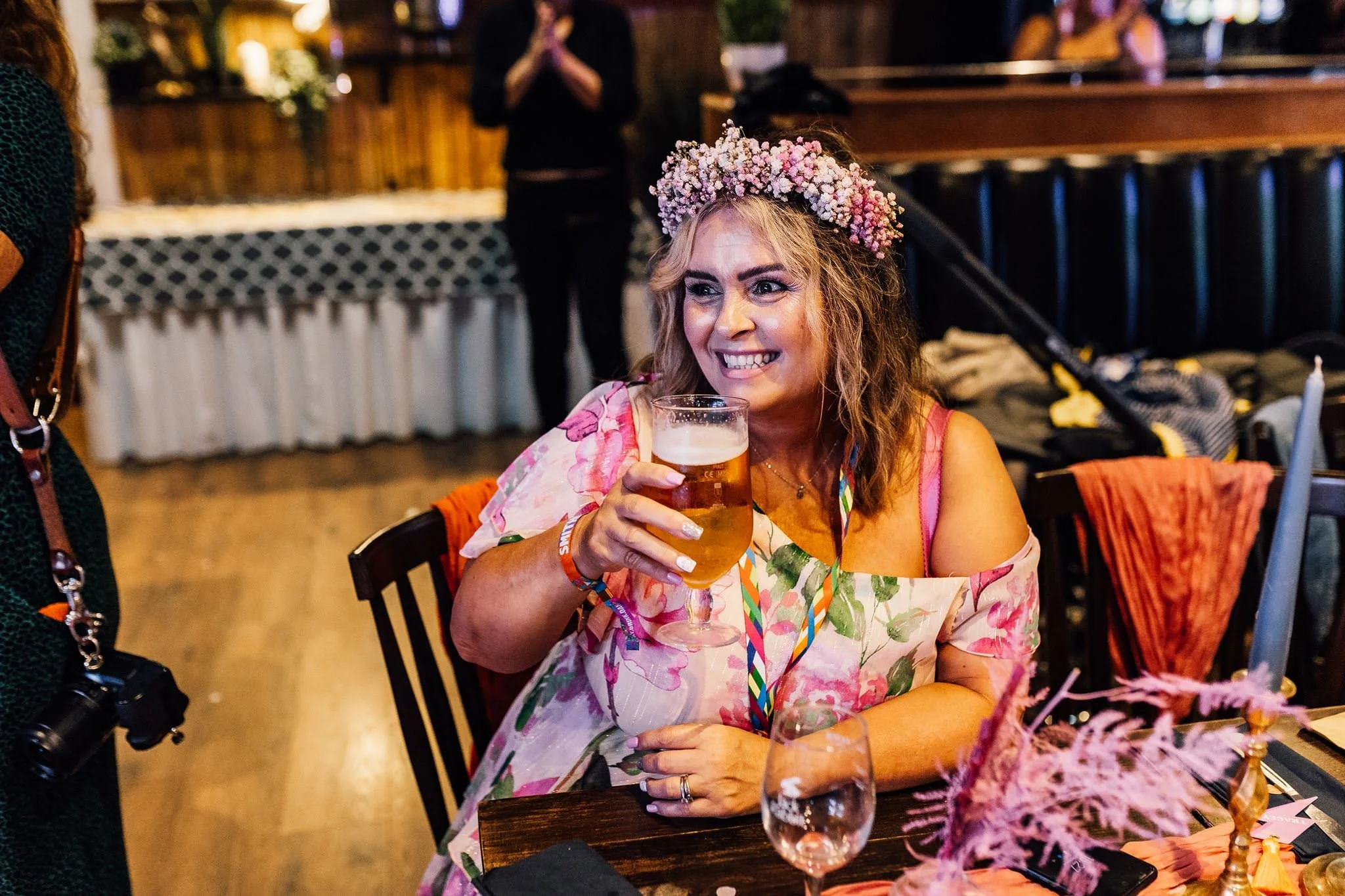 A wedding guest with glitter makeup holding a drink