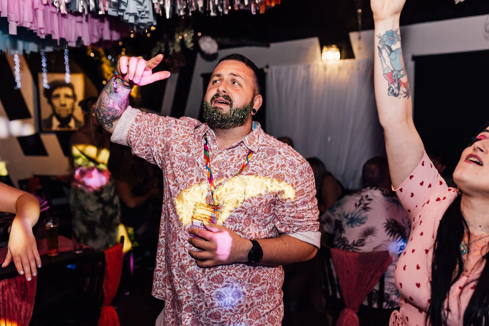 A guest in a patterned shirt dancing with his arm raised