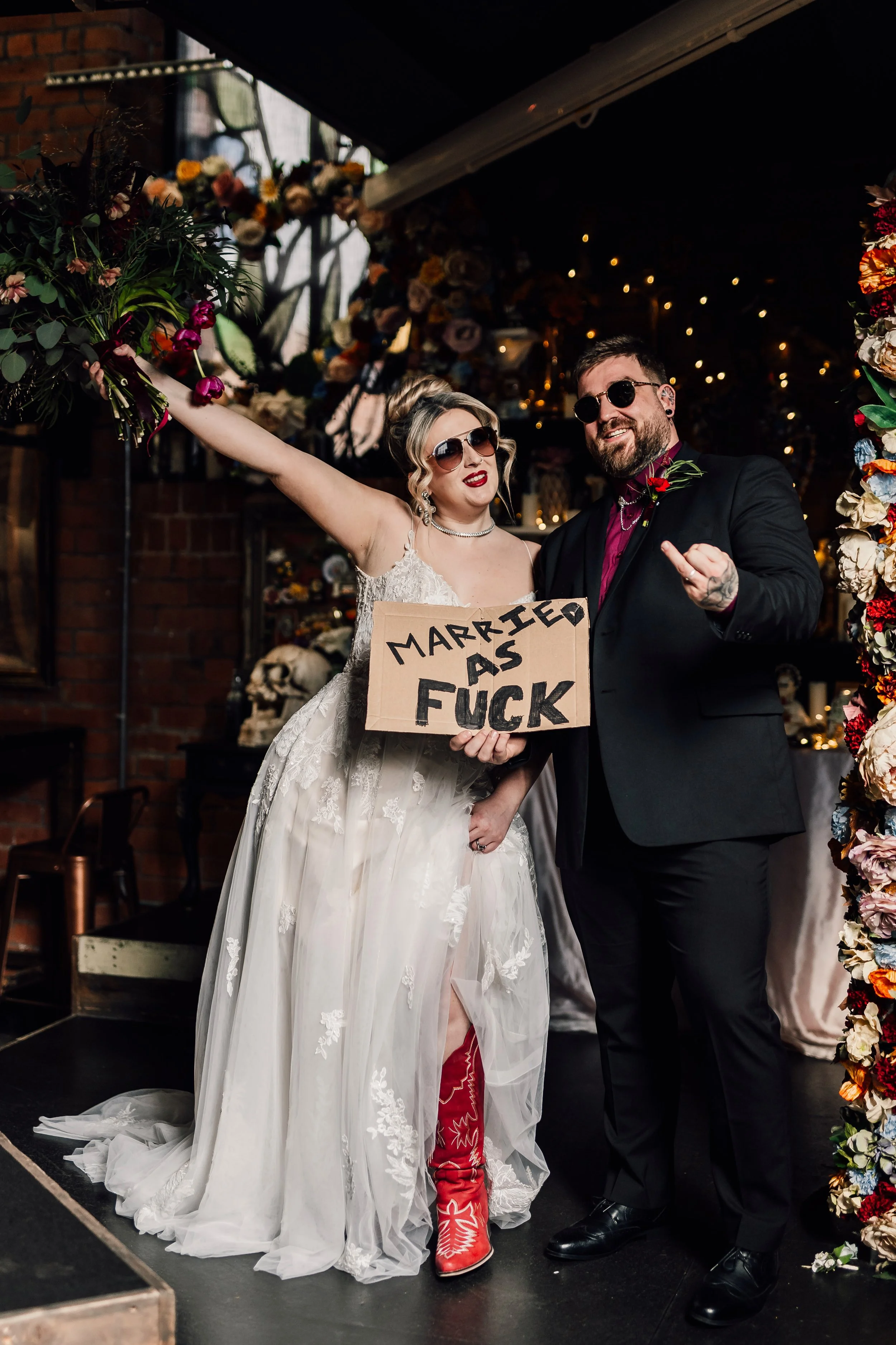 Fun alternative wedding couple with bold “married as fuck” sign at Church Temple of Fun wedding venue Sheffield