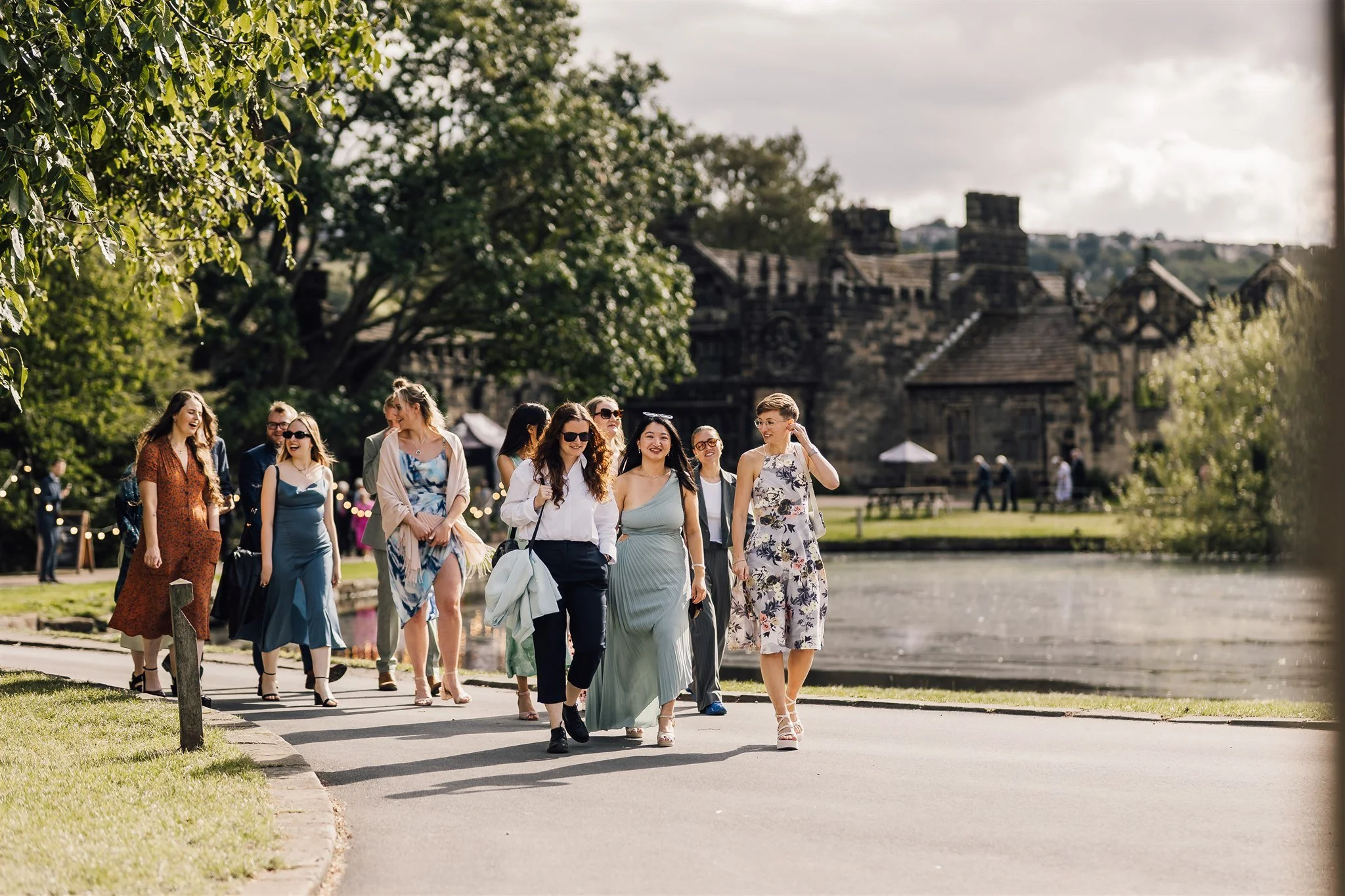 Wedding guests walking together by the lake at East Riddlesden Hall in West Yorkshire