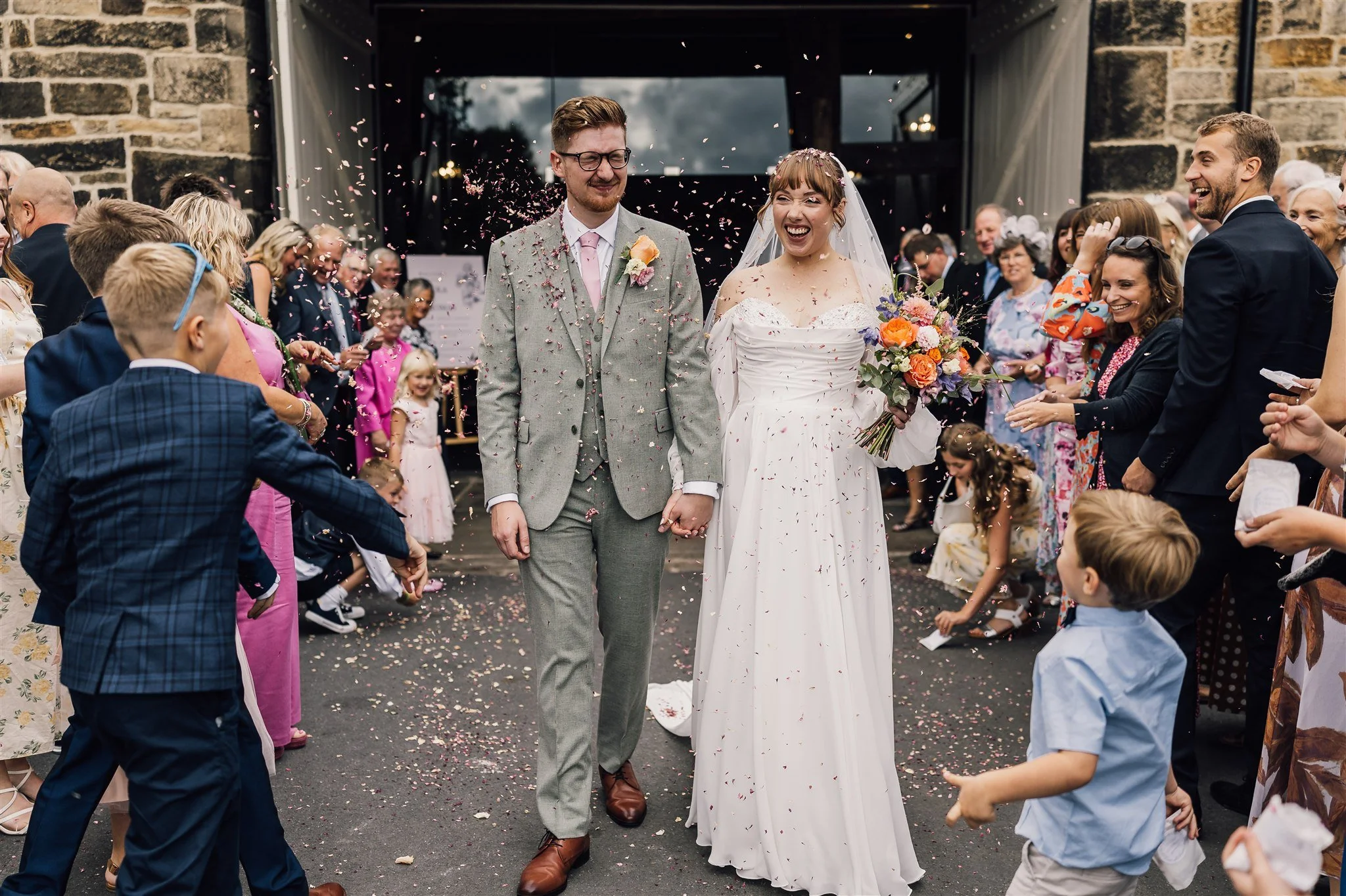 Confetti moment outside East Riddlesden Hall with bride and groom surrounded by guests