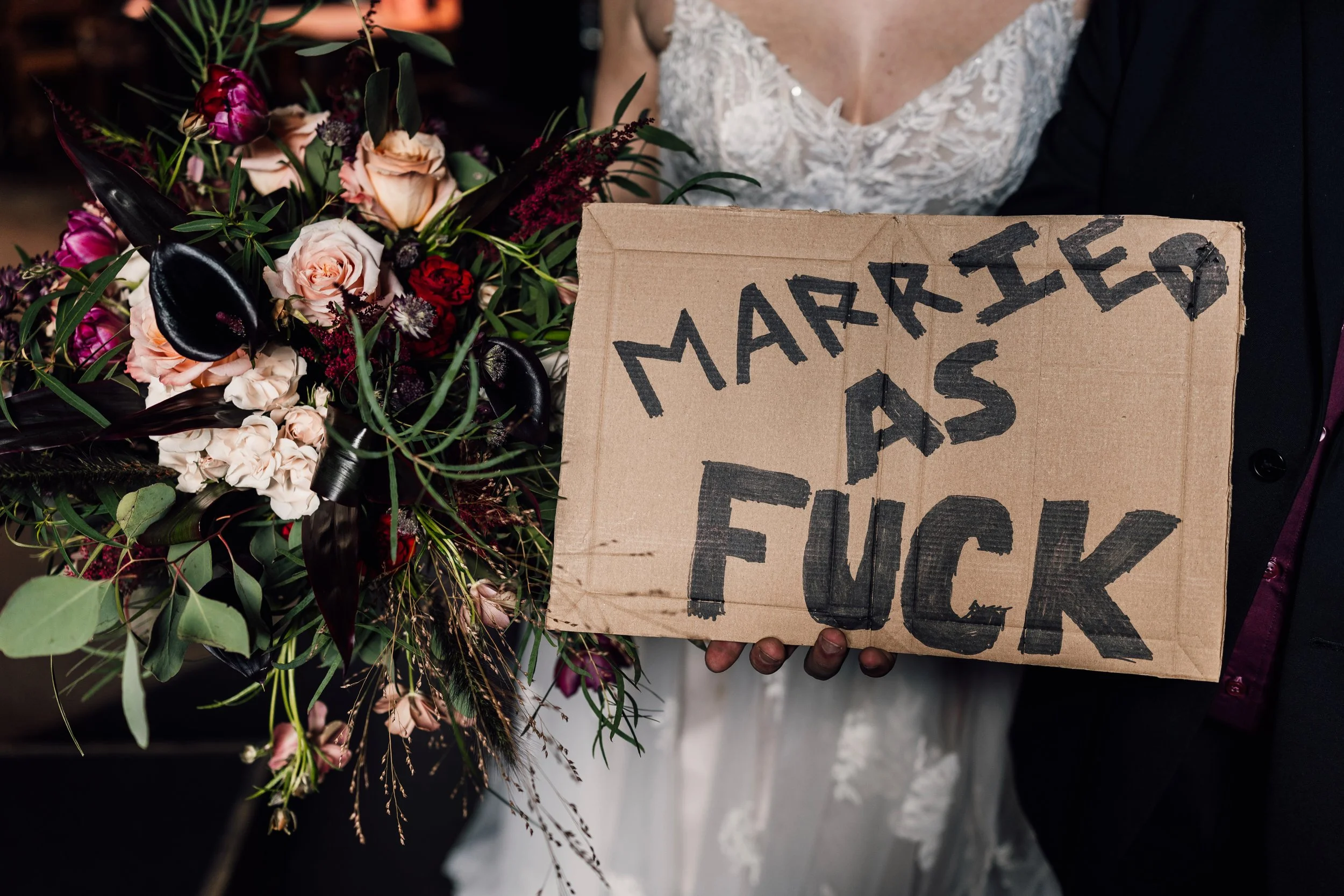 Fun alternative wedding couple with bold “married as fuck” sign at Church Temple of Fun wedding venue Sheffield