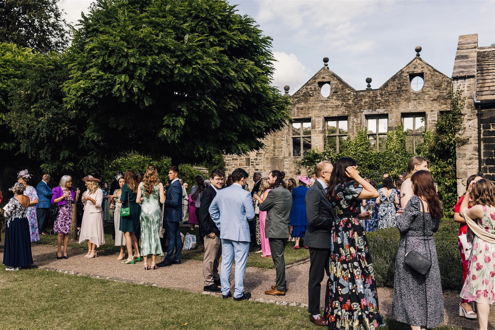 Wedding guests gathered outside East Riddlesden Hall with historic building backdrop