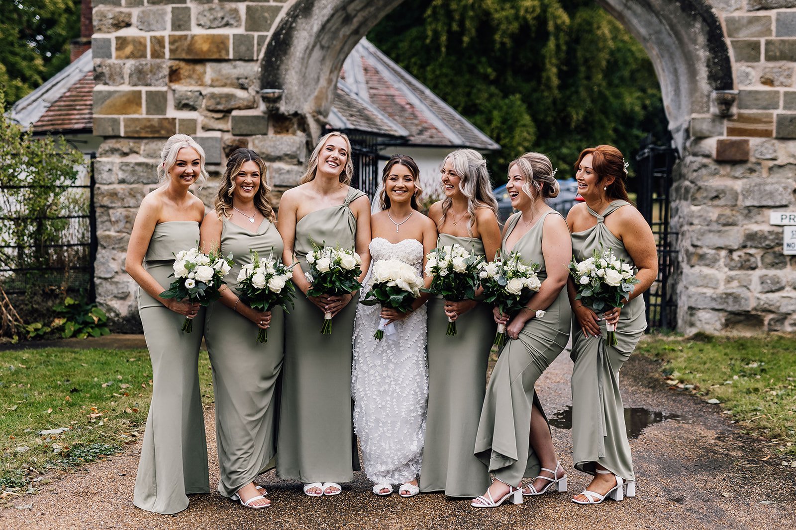 Charlotte and her bridesmaids beside a stone arch