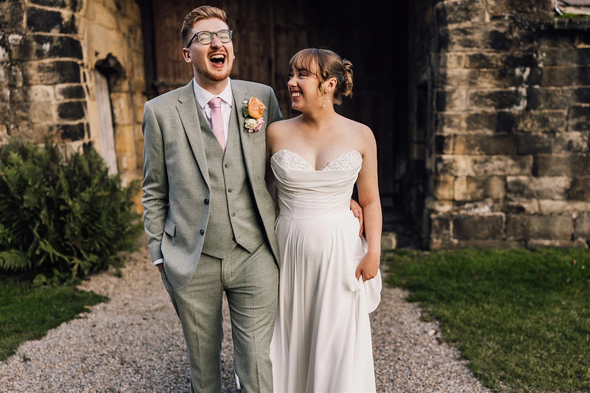 Bride and groom laughing together outside East Riddlesden Hall after their wedding ceremony