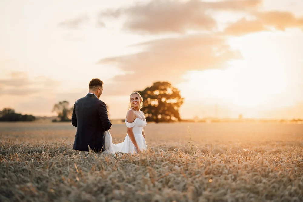 A newly married couple in a Yorkshire field at sunset