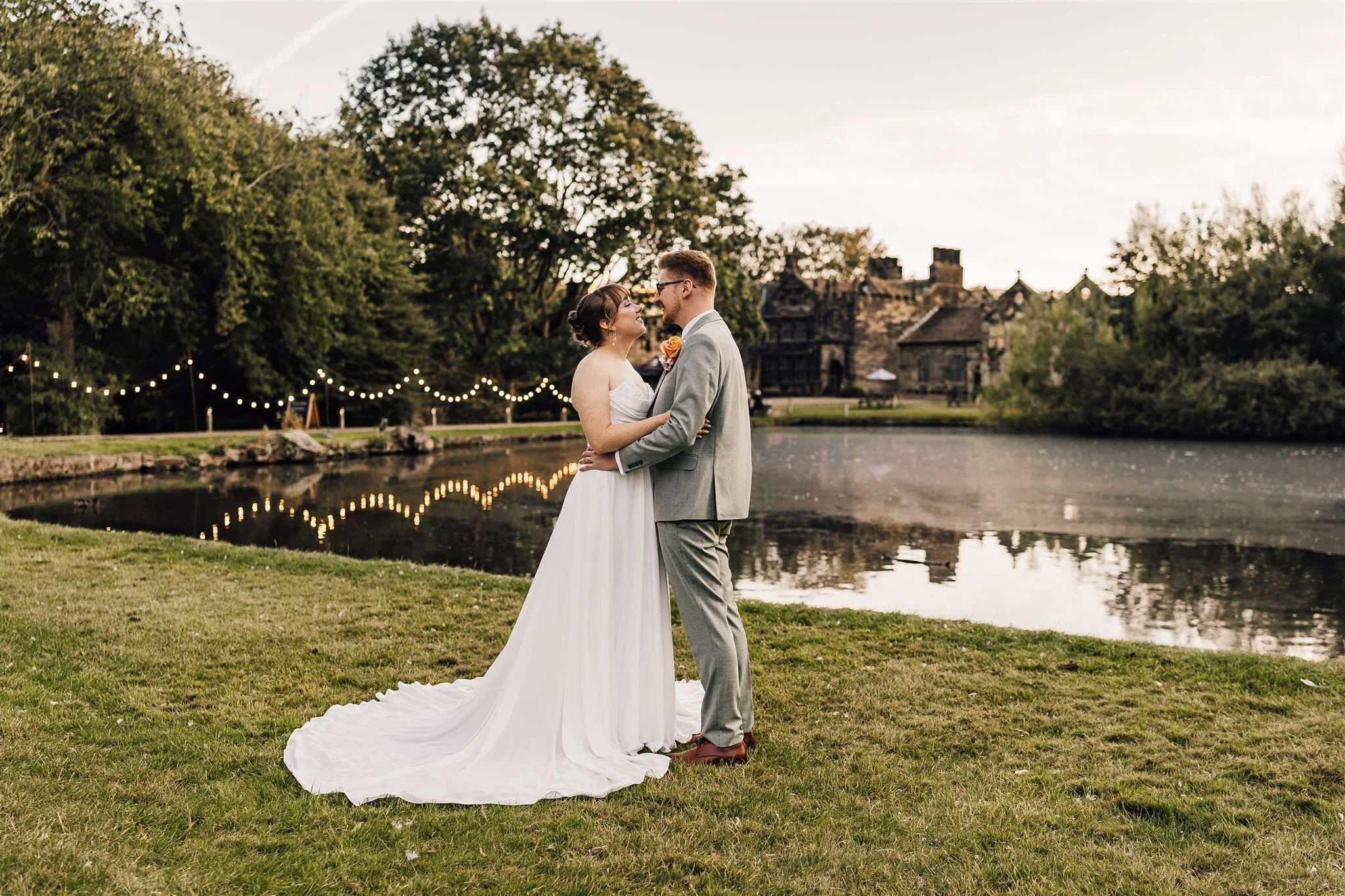 Wide couple portrait at East Riddlesden Hall showing lake and venue at sunset
