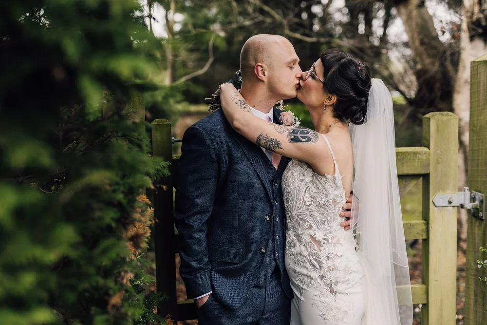 Lucy and Jack sharing a kiss in the garden at Tickton Grange