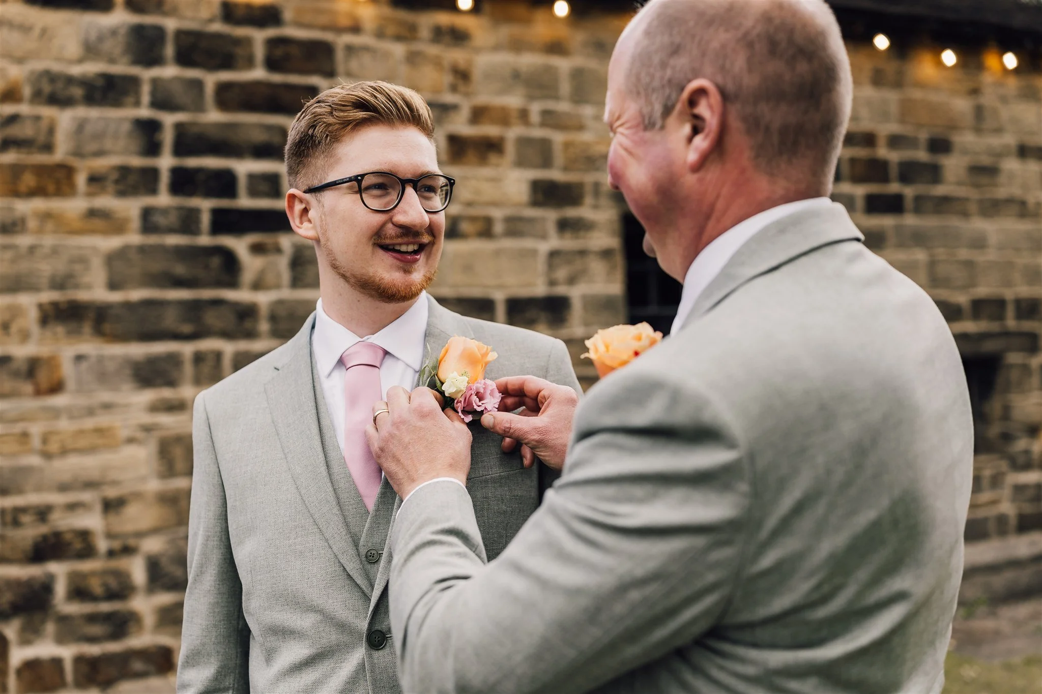 Groom getting buttonhole adjusted before ceremony at East Riddlesden Hall in West Yorkshire