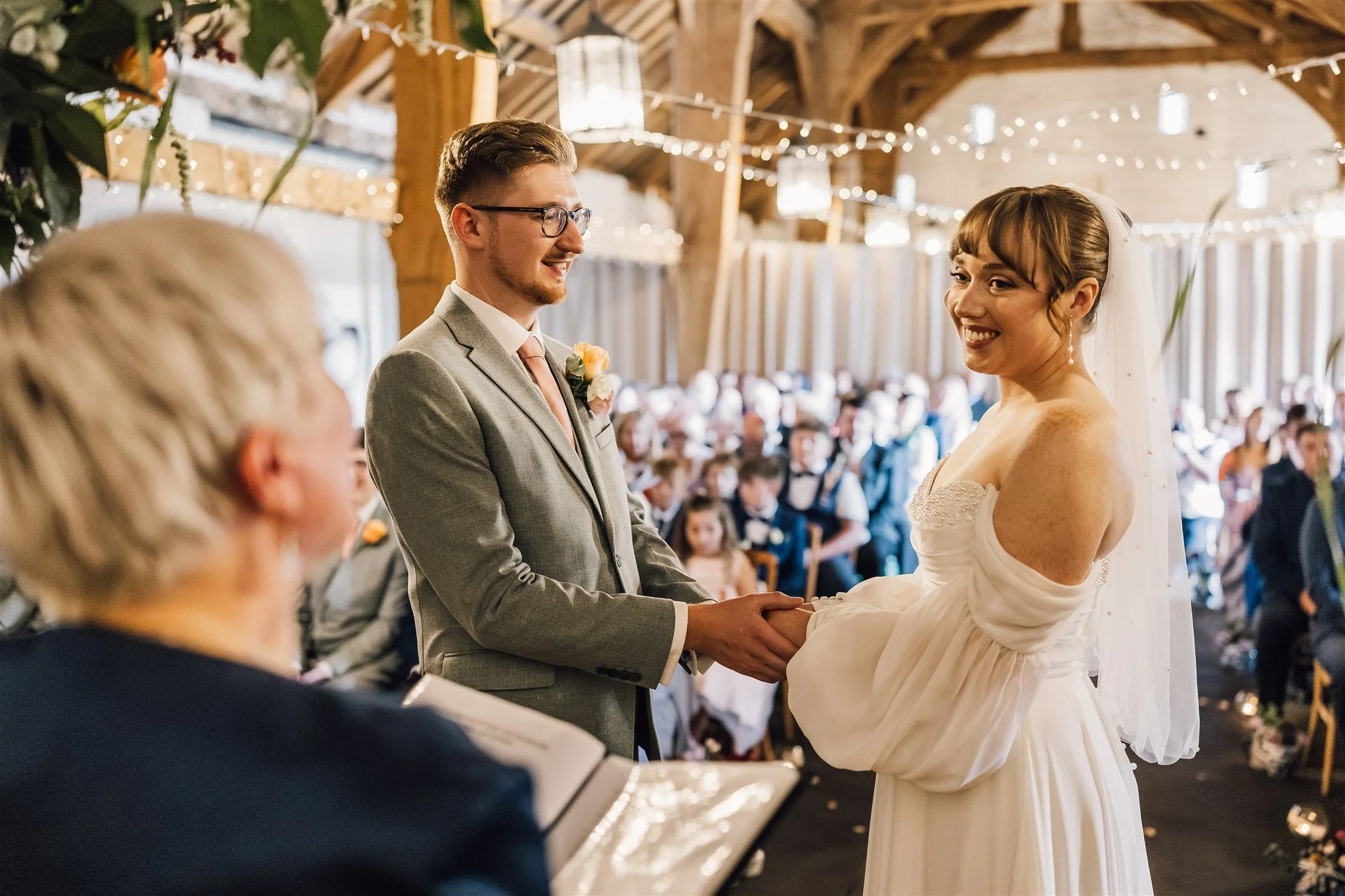 Bride and groom holding hands during wedding ceremony at East Riddlesden Hall
