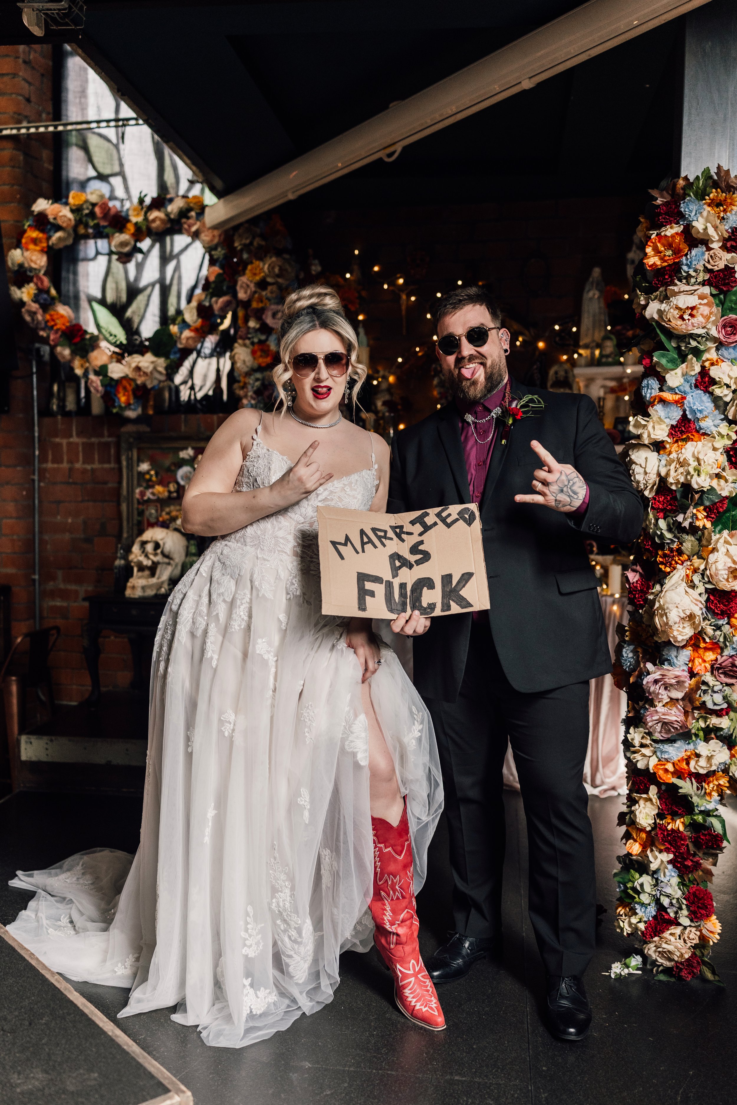 Fun alternative wedding couple with bold “married as fuck” sign at Church Temple of Fun wedding venue Sheffield
