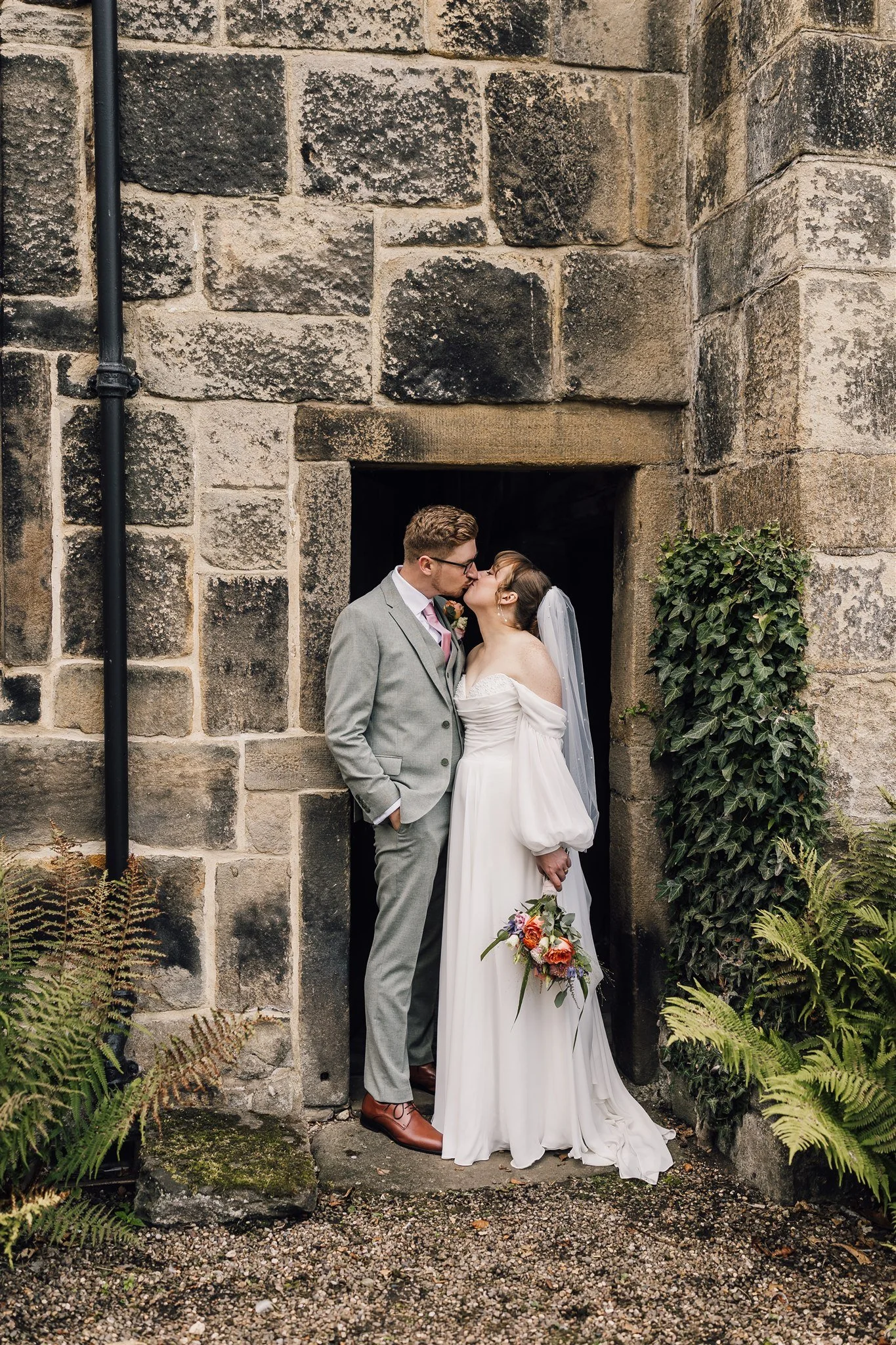 Bride and groom kissing in stone doorway at East Riddlesden Hall in West Yorkshire