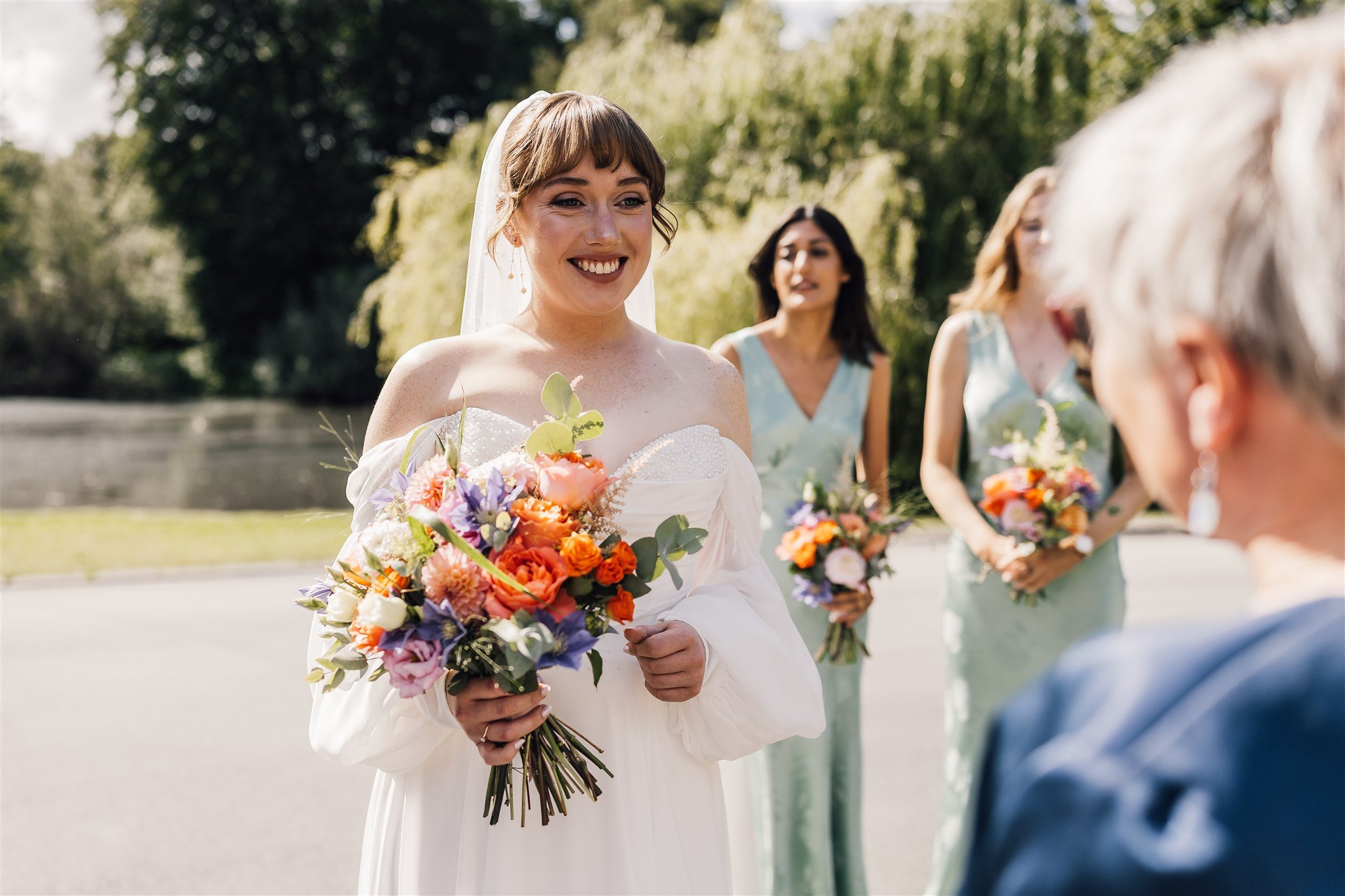 Bride walking with bridesmaids holding colourful bouquets at East Riddlesden Hall in West Yorkshire