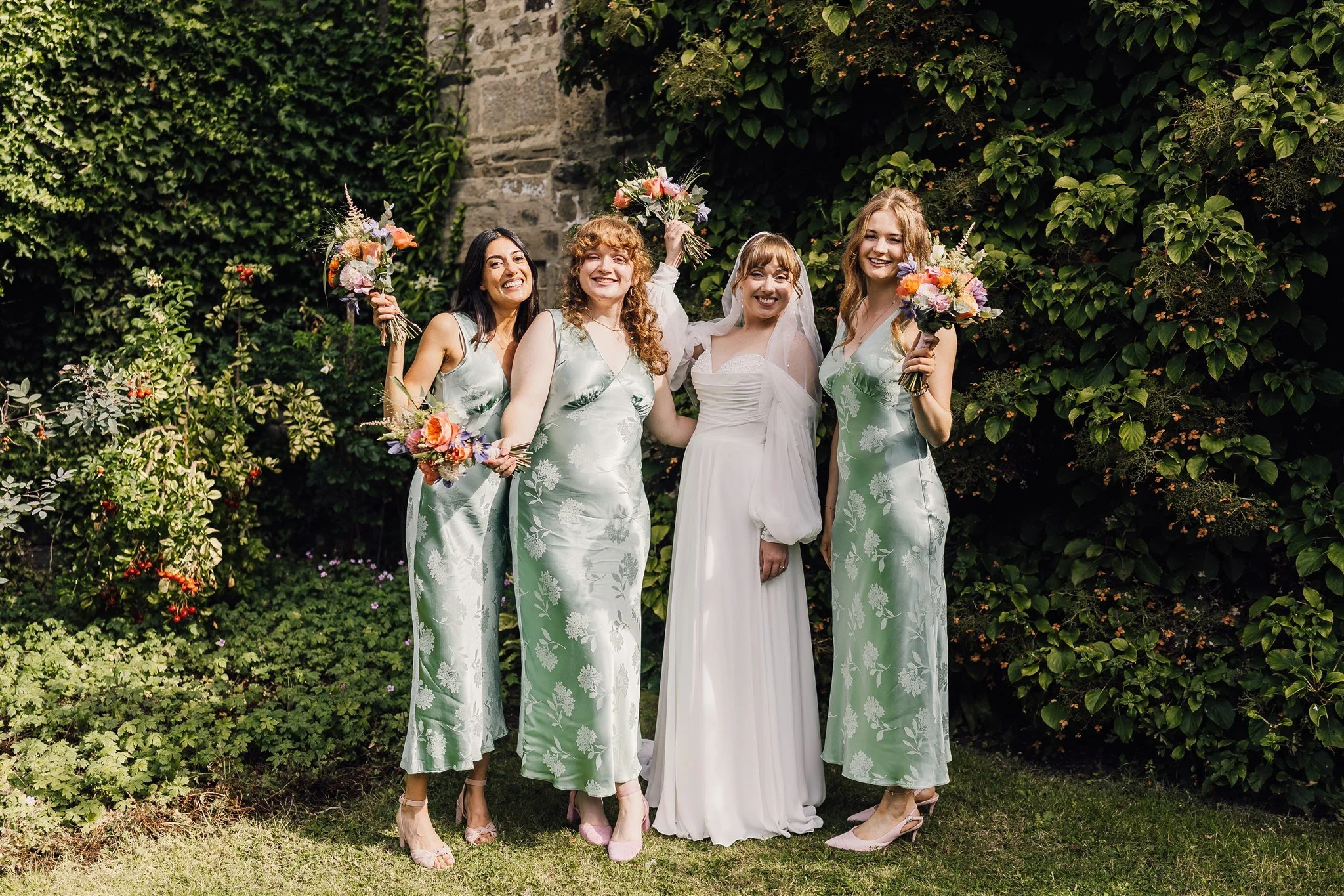Bride with bridesmaids holding bouquets at East Riddlesden Hall in West Yorkshire