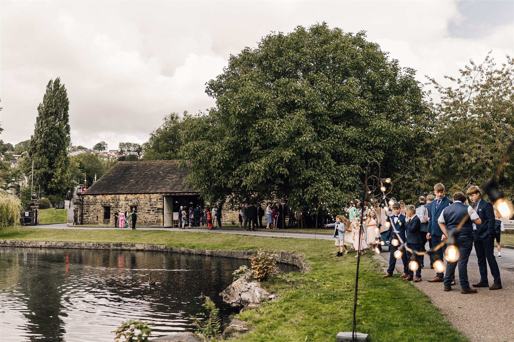Wedding guests gathering outside by the lake at East Riddlesden Hall in West Yorkshire