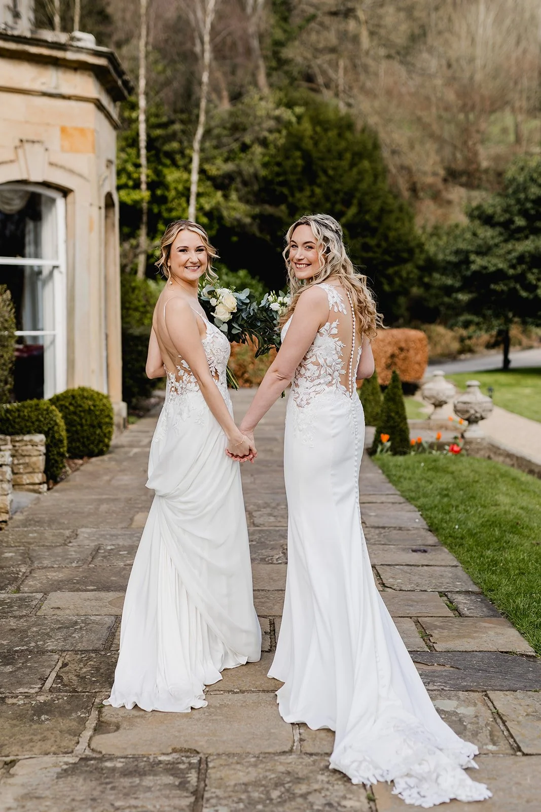 Two brides walking hand in hand outside Hackness Grange during their North Yorkshire wedding