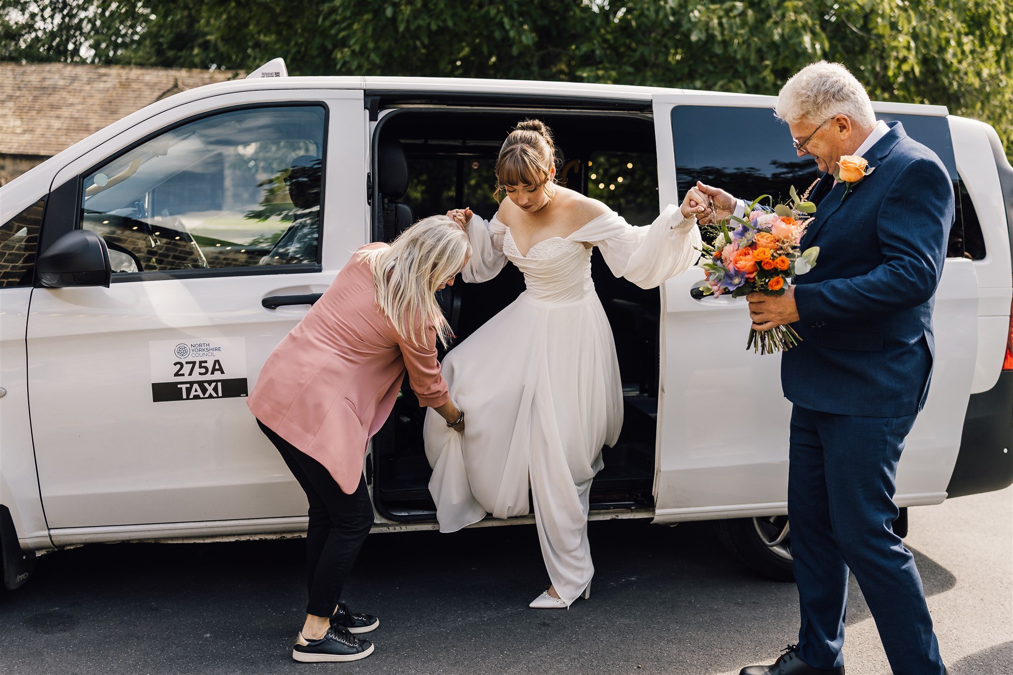 Bride arriving at East Riddlesden Hall wedding venue stepping out of car with family