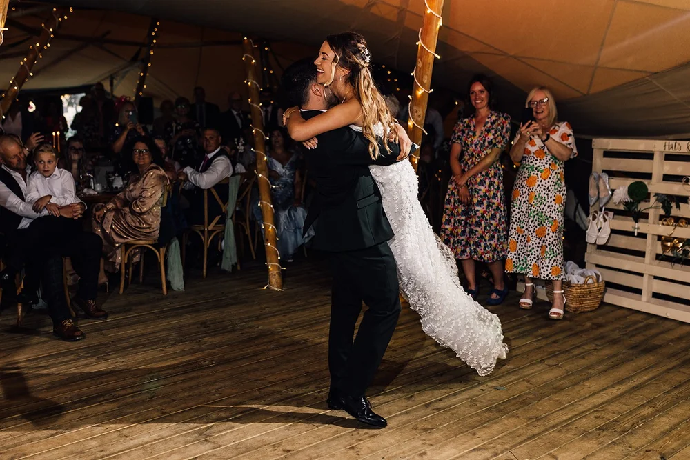 Rory lifting Charlotte during their first dance in the fairy-lit Scrivelsby tipis