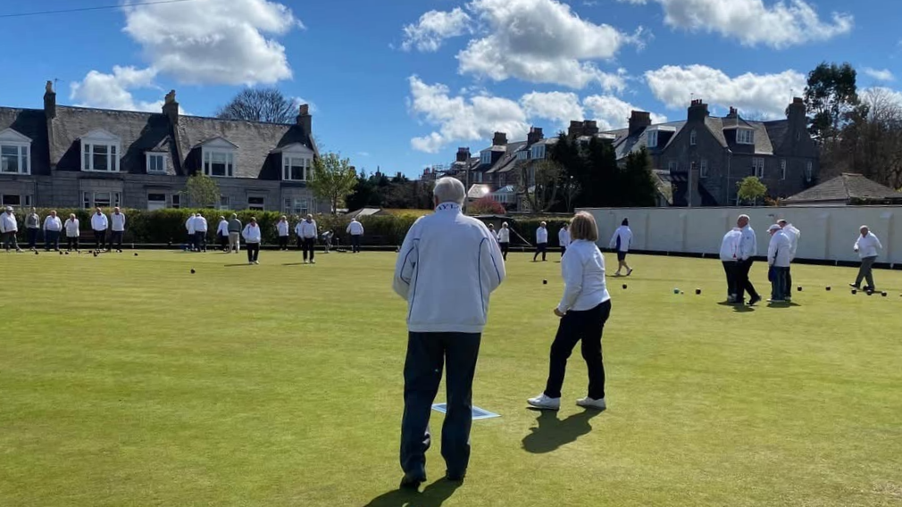 Bowlers playing a bowls game on grass.