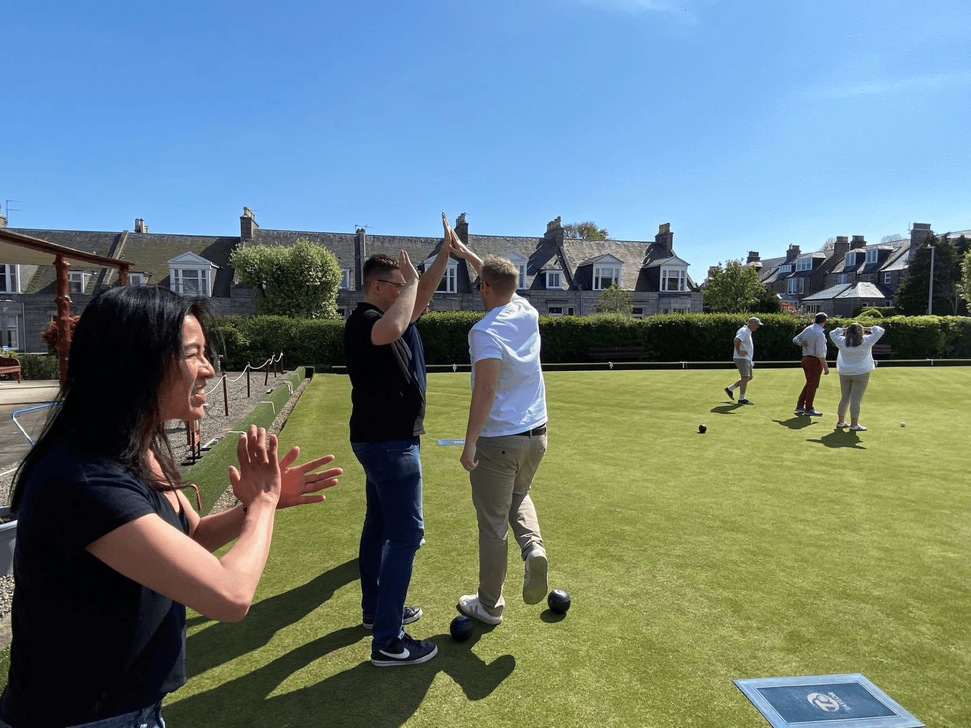 Woman clapping at a lawn bowl game on a green