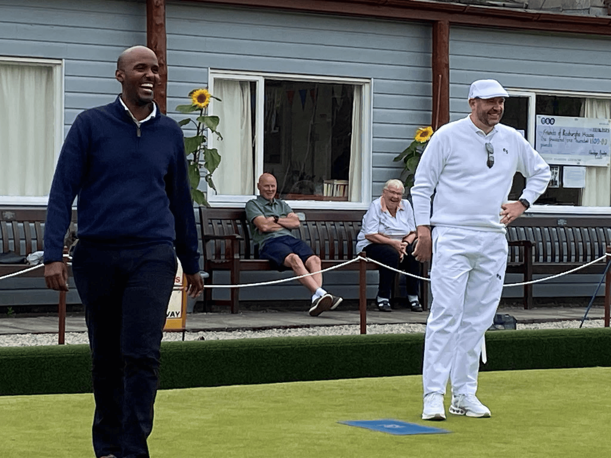 Two men standing on a lawn bowl green smiling
