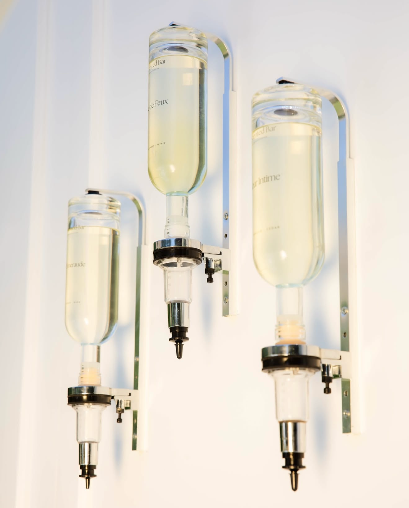 Three IV fluid bags hanging on a white wall in a medical setting.