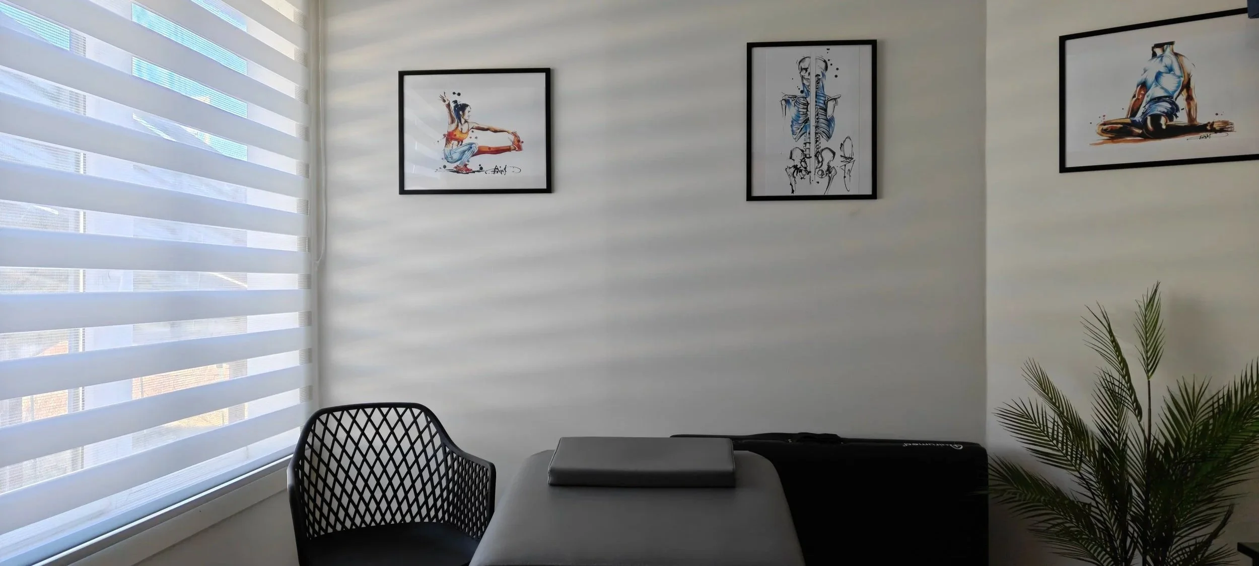 Bureau avec une chaise, une table avec un ordinateur portable, des cadres d'art sur les murs et une plante verte dans un coin.