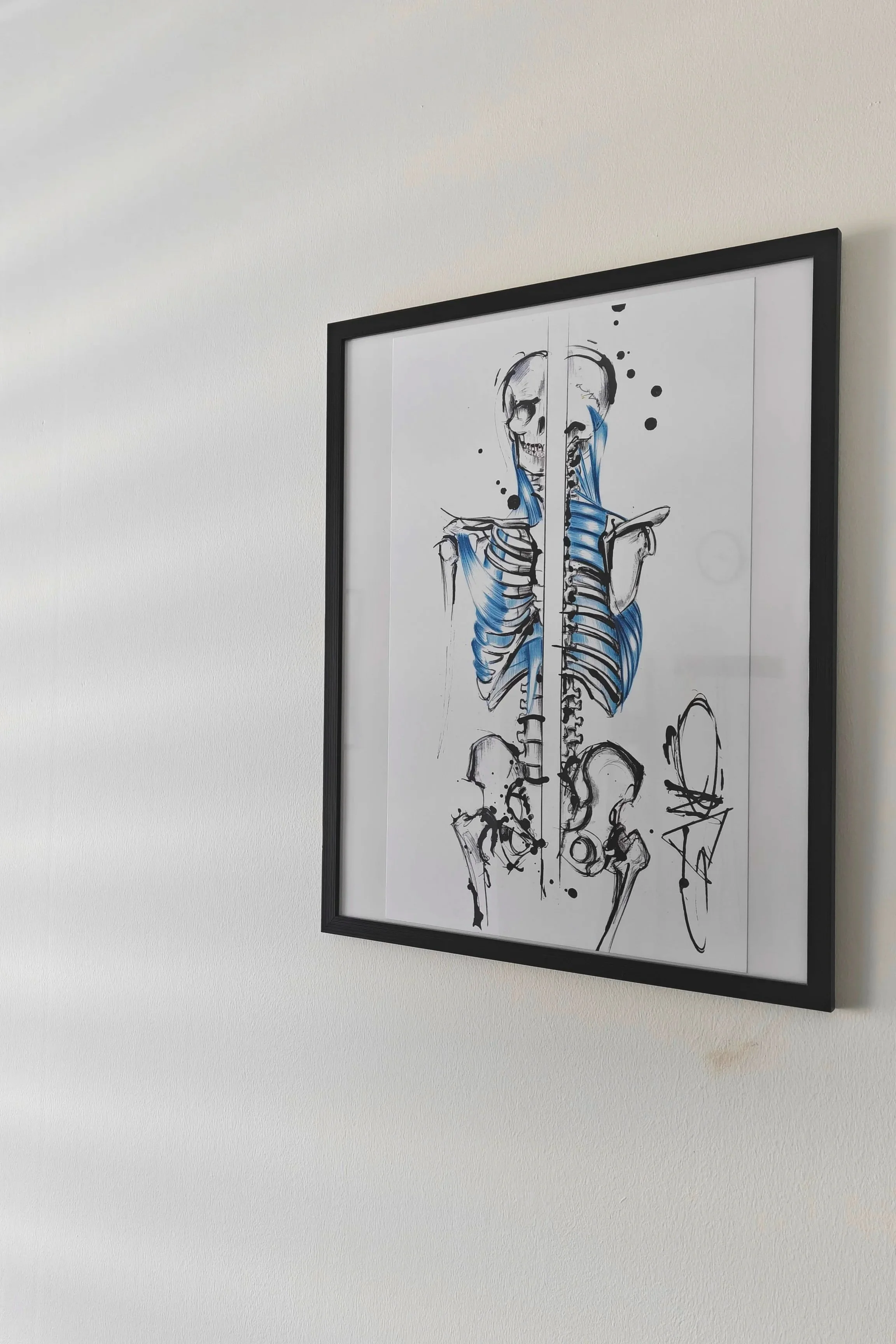 Dessin artistique d'un squelette humain en style abstrait, avec des traits noirs et des touches de bleu, affiché dans un cadre noir suspendu au mur.