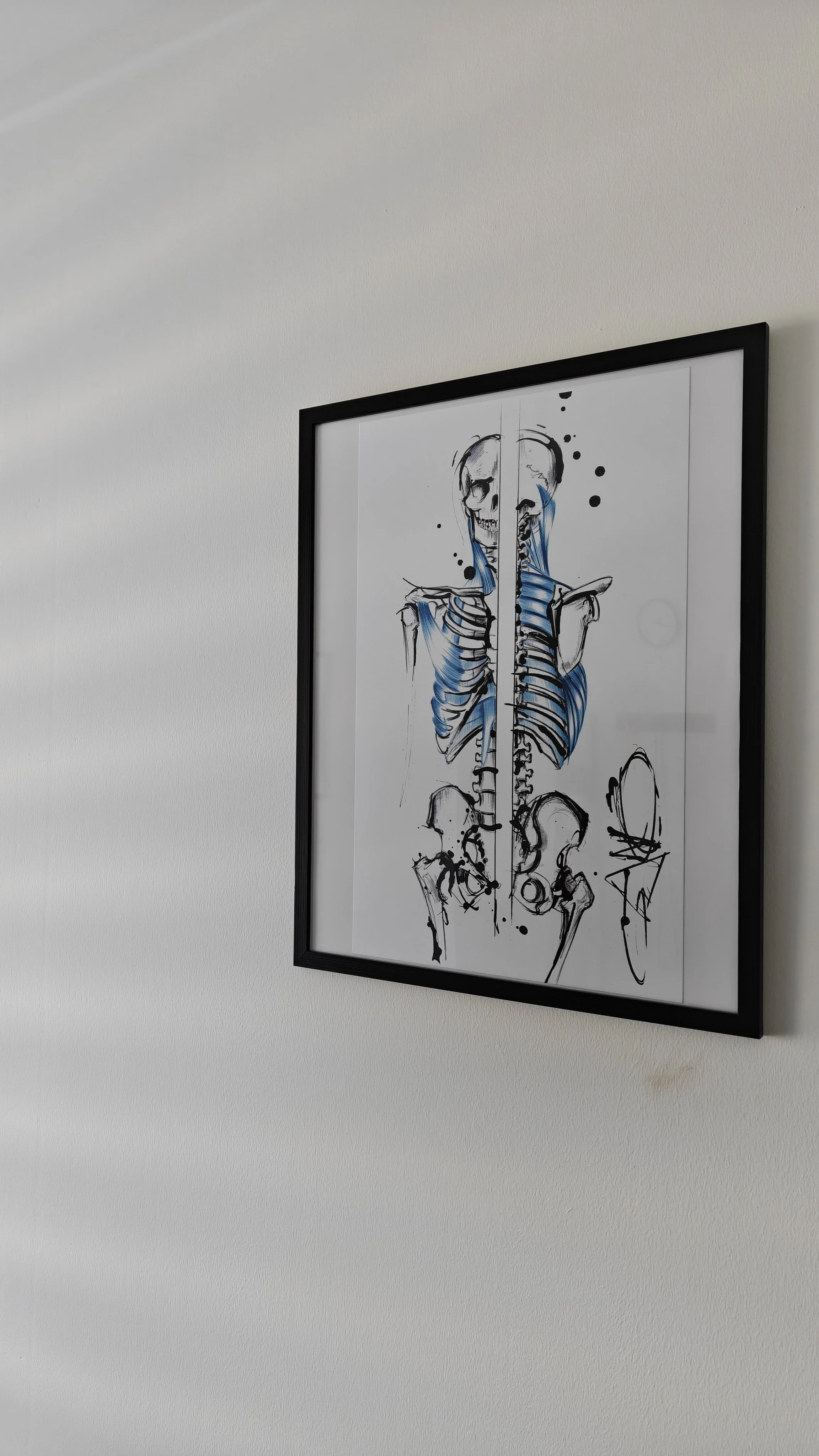 Dessin artistique d'un squelette humain avec des accents bleus, architectural et abstrait, accroché à un mur blanc