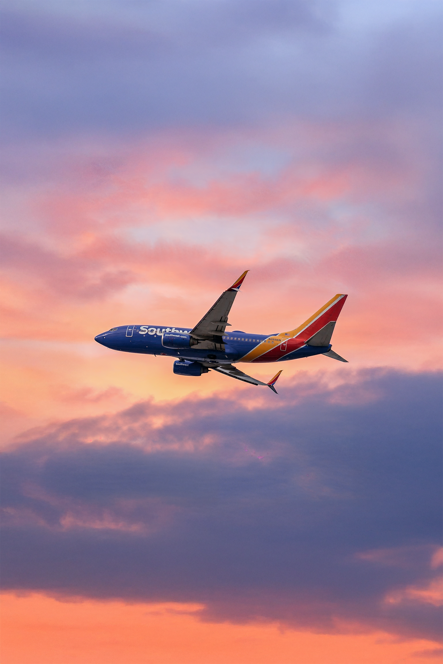 An airplane flying in the sky during sunset with colorful clouds.