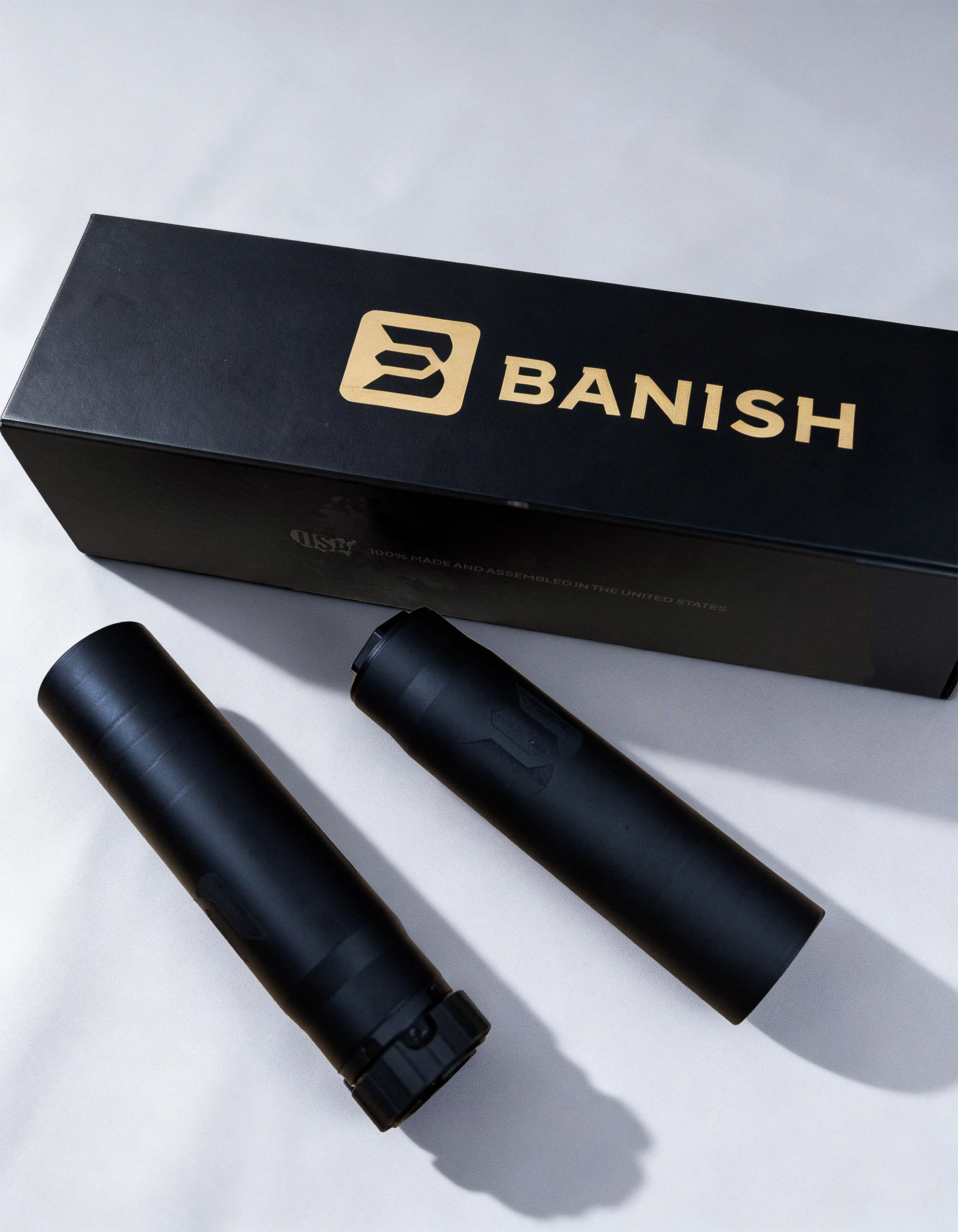 Black box labeled 'BANISH' with a logo, two black cylindrical objects, and a marker on a white surface.