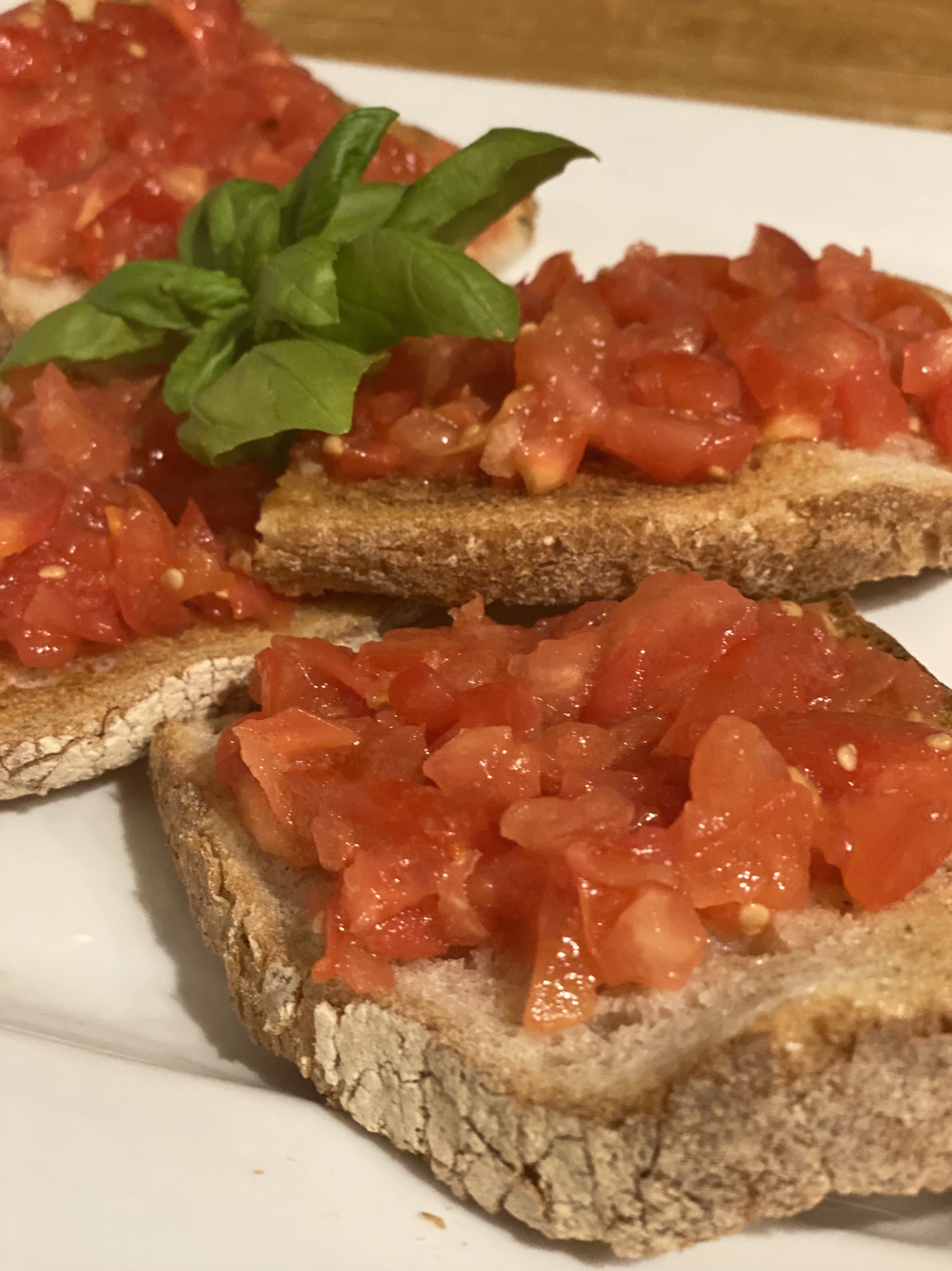 Sliced bread topped with fresh tomato bruschetta, garnished with basil leaves.