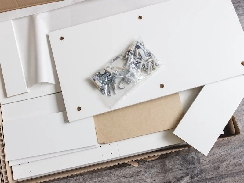 Flat-pack furniture panels and a bag of fixings laid out ready for assembly