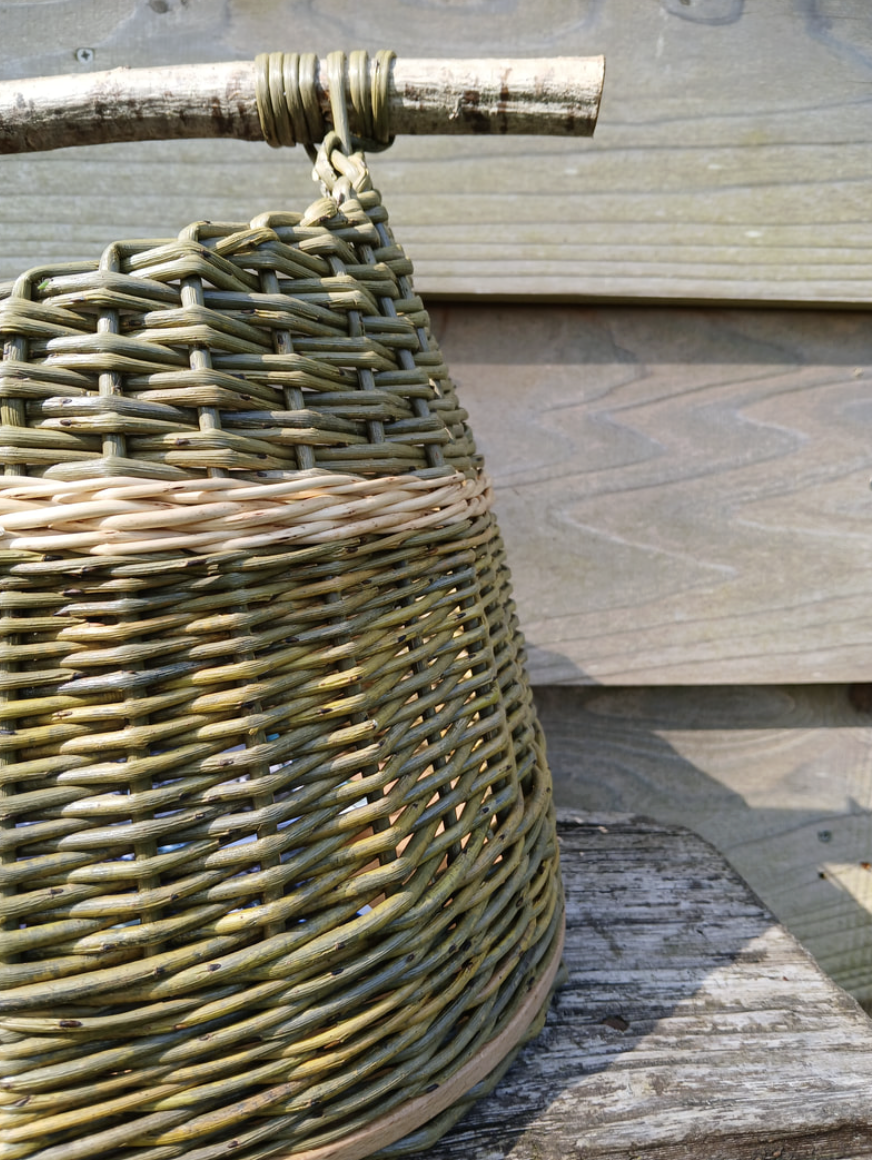 Close-up of a basket hanging from a wooden stick against a wooden background.