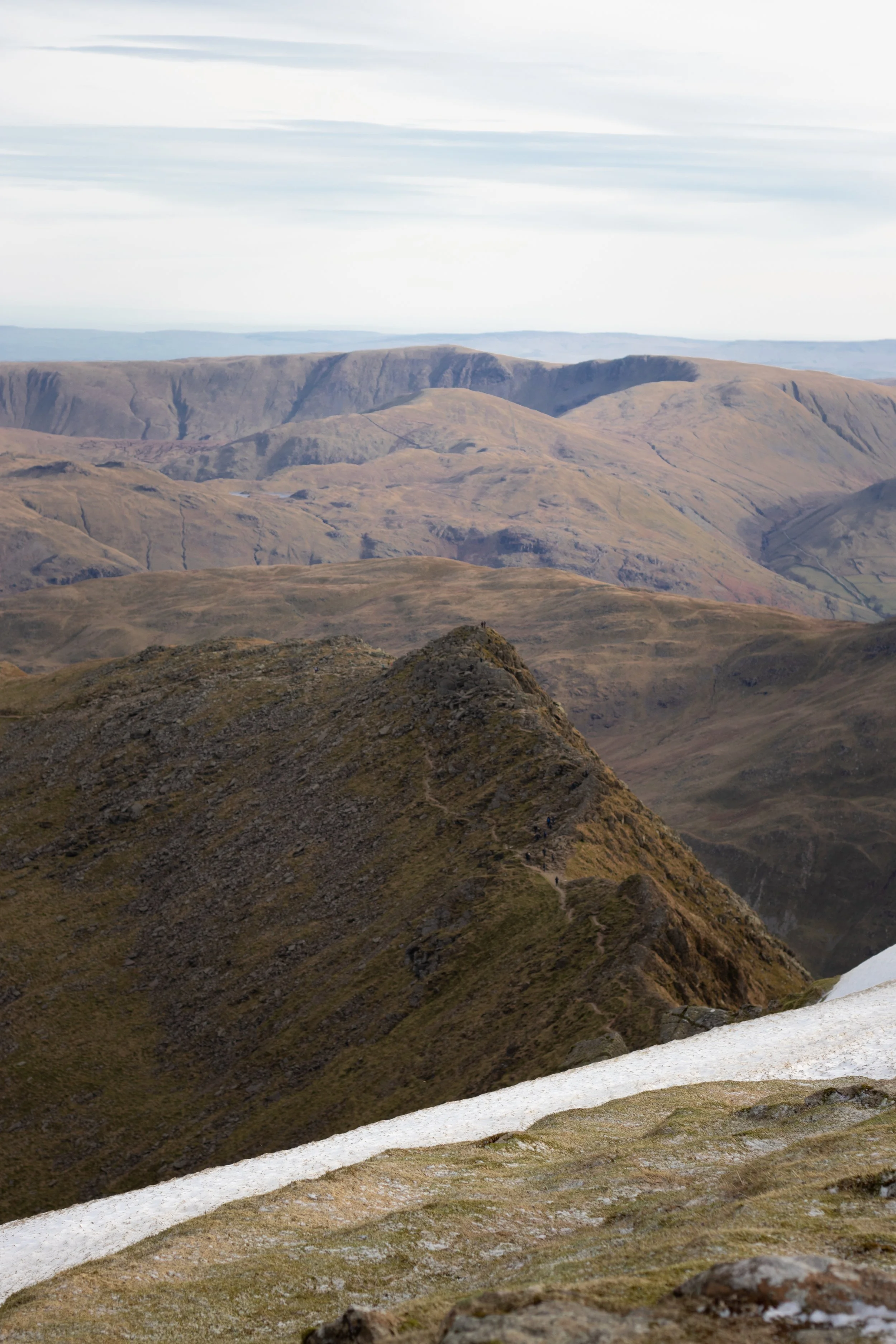 Scenic view of Striding Edge, Helvellyn with a small patch of snow in the foreground in The Lake District, United Kingdom.