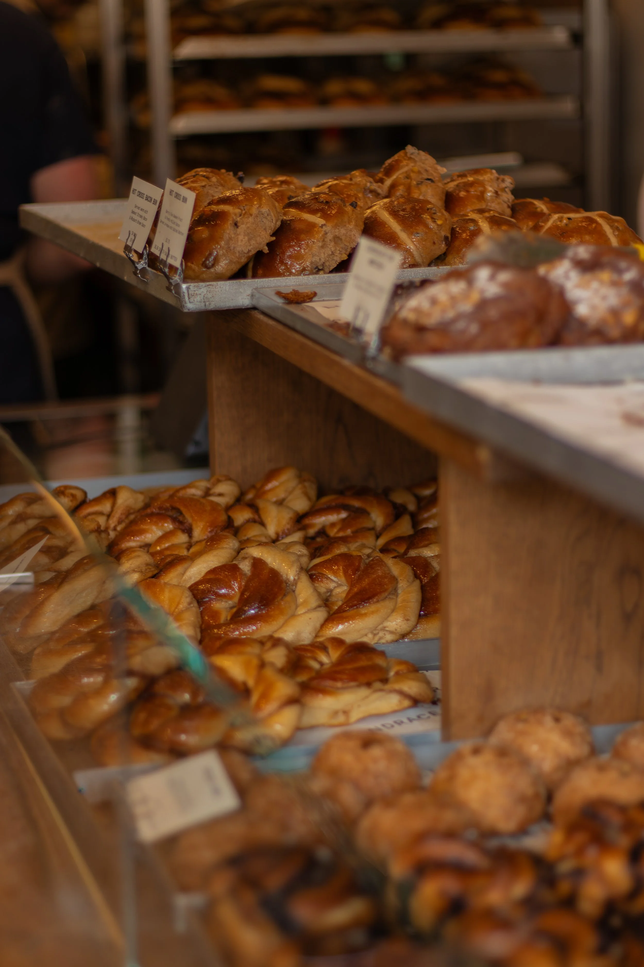 Display of baked goods such as donuts and pastries on metal trays in a bakery or store.