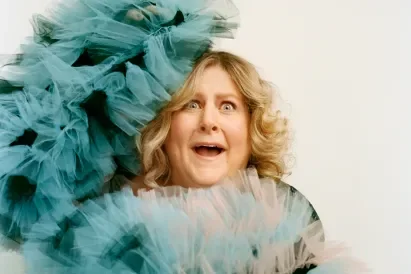 Bridget Everett, actress, comedian, singer, with an excited expression on her face, surrounded by blue tulle fabric.