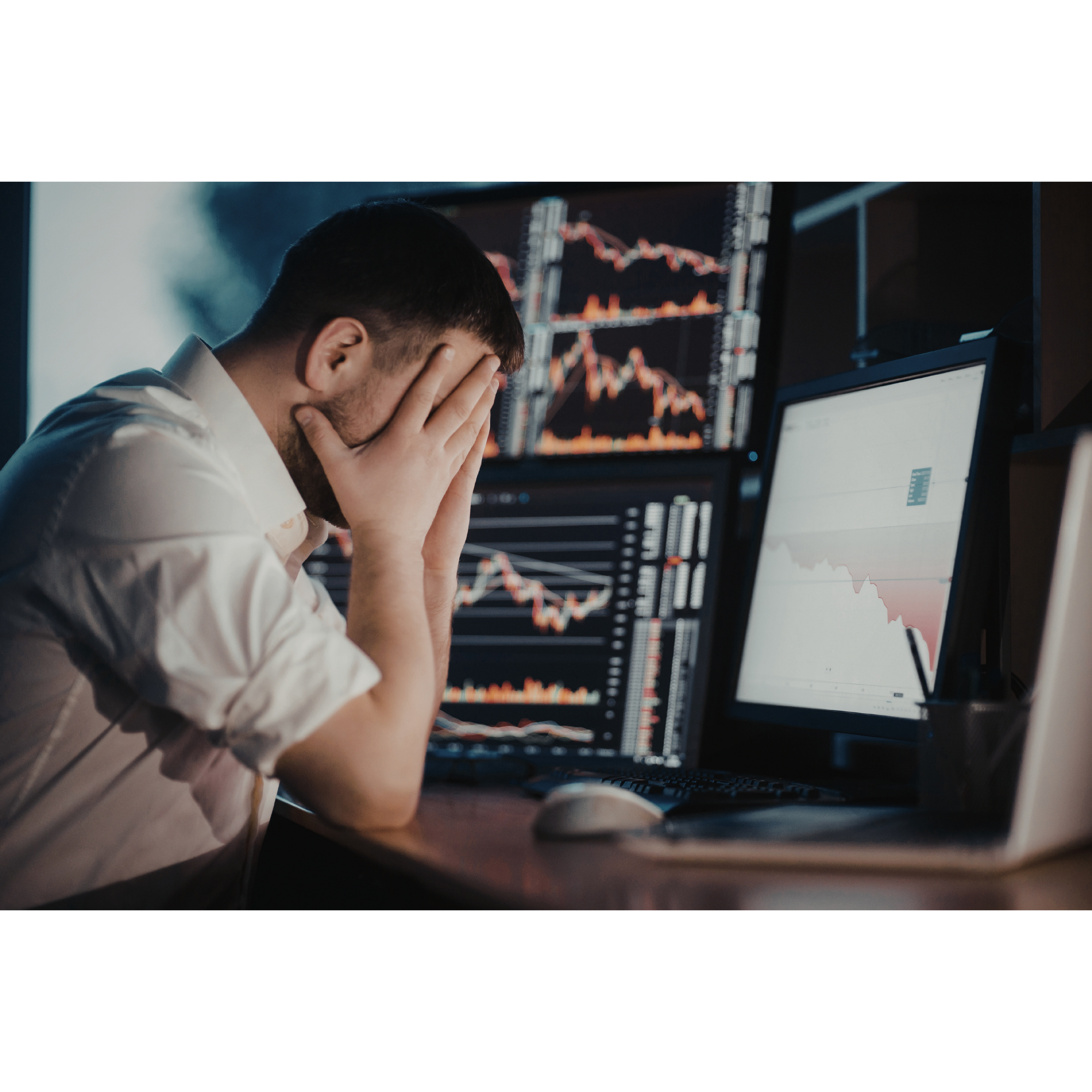 Frustrated man watching multiple computer monitors displaying stock market charts