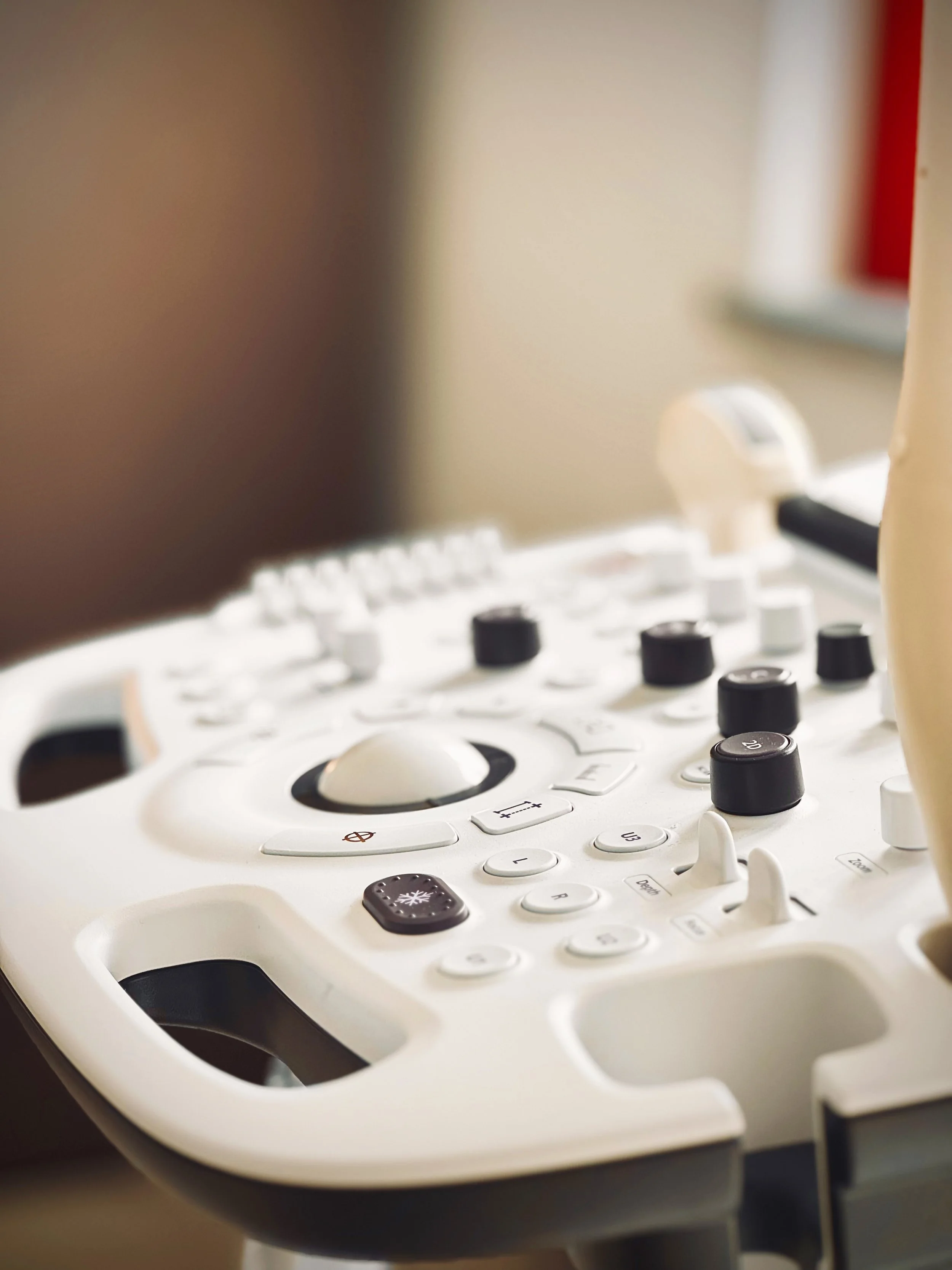 Apparecchiatura medica per ecografie con vari pulsanti e manopole, bianca con dettagli neri.