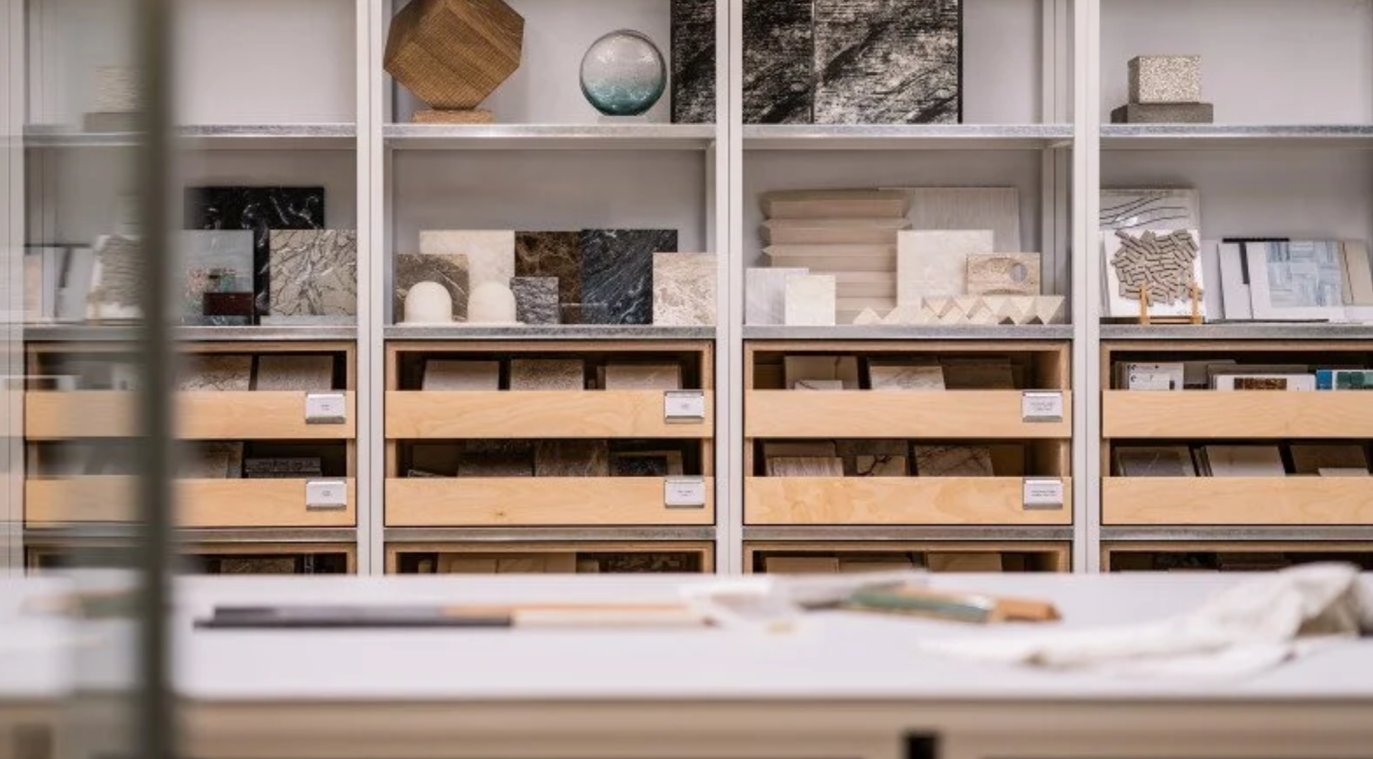 Store shelving with samples of tile and stone, with a table in the foreground.