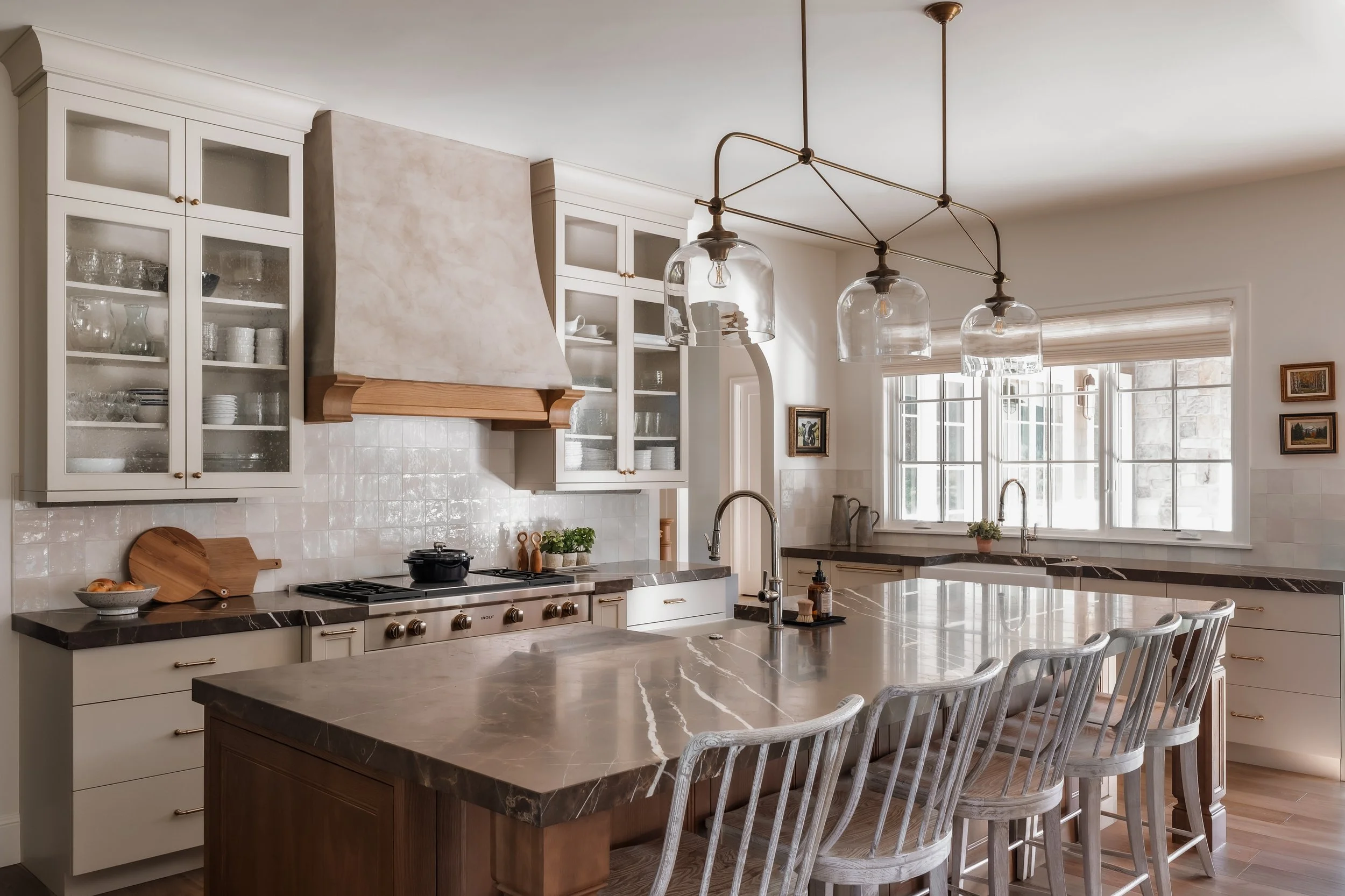 Bright kitchen with white cabinets, marble countertops, a large island with seating, and a window with blinds