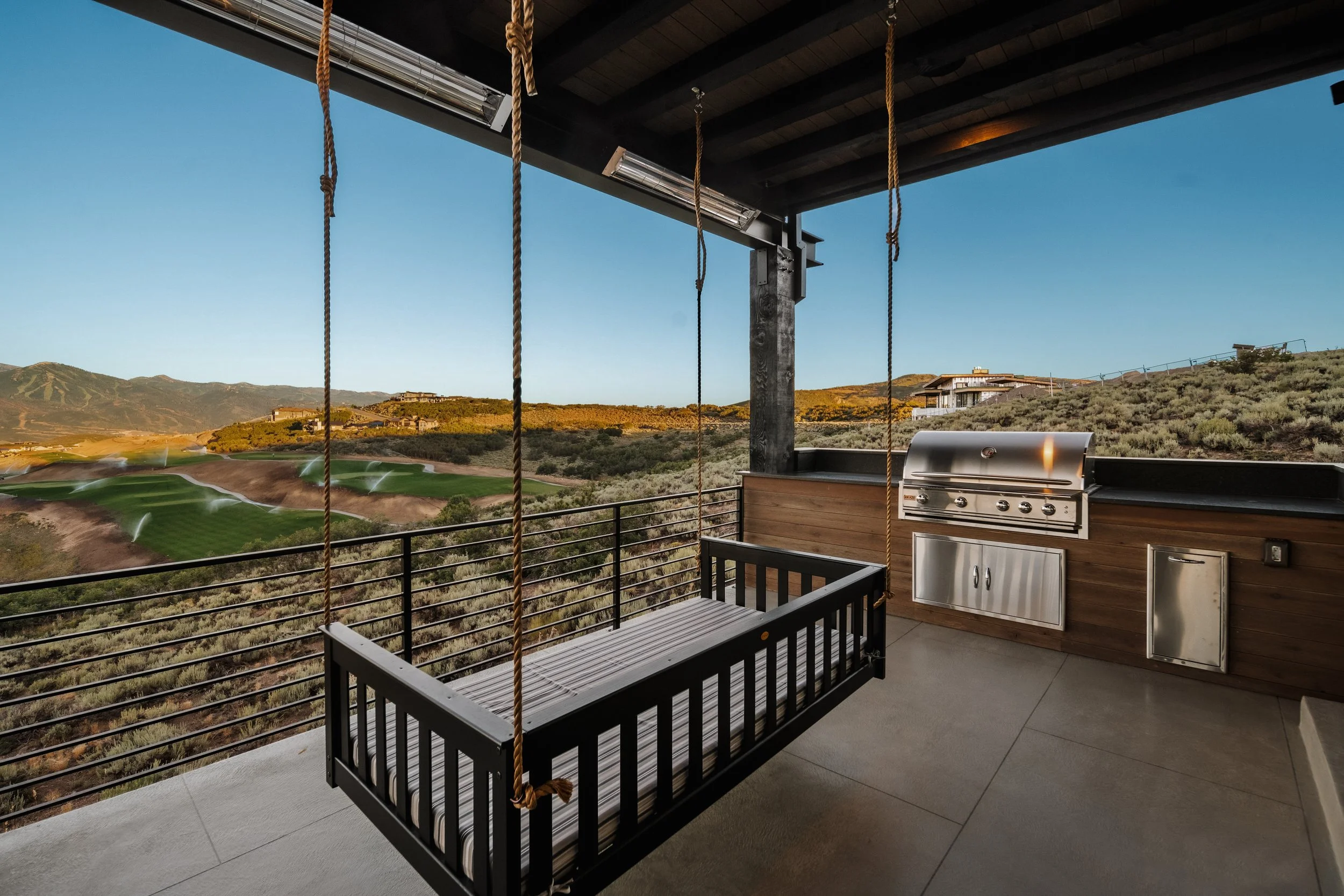 Balcony with black porch swing, stainless steel grill, and mountain view.