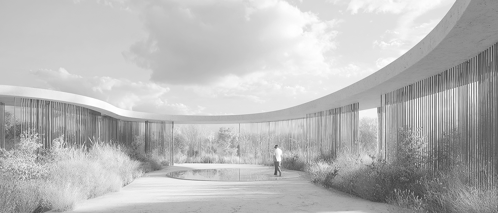 A modern architectural structure with curved roof and vertical metal slats on either side, surrounding a pathway with a small puddle, some bushes, and a person walking along the pathway.