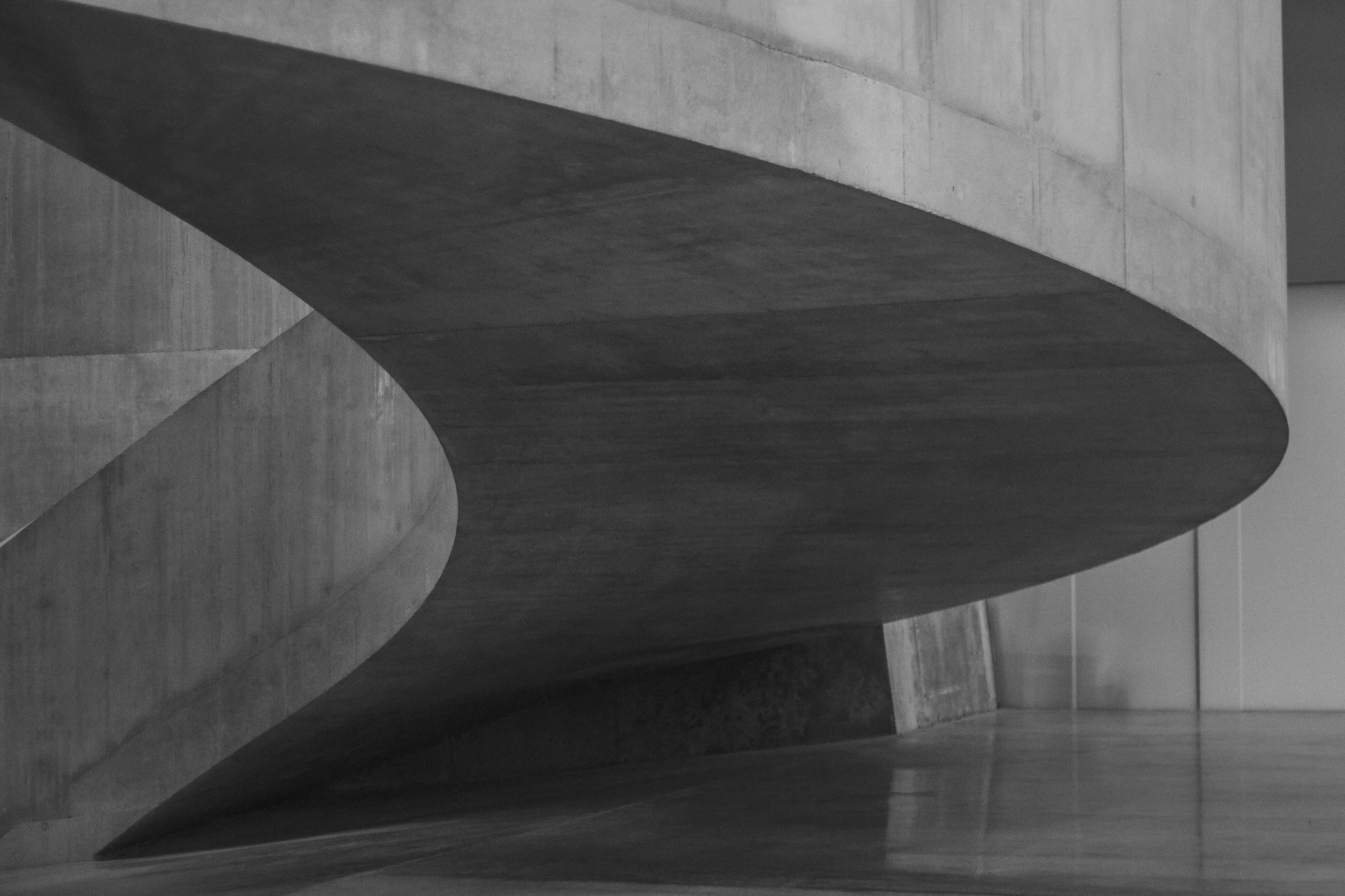 Black and white photograph of abstract architectural concrete structures with curved and angled surfaces.