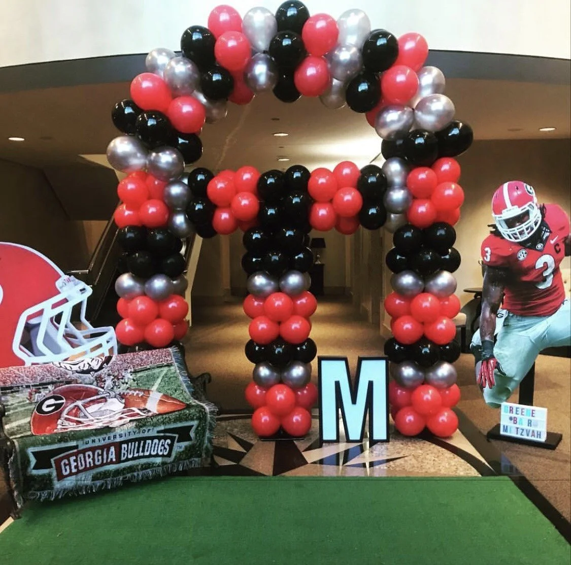 Decorative arch made of red, black, and silver balloons at a Georgia Bulldogs-themed event