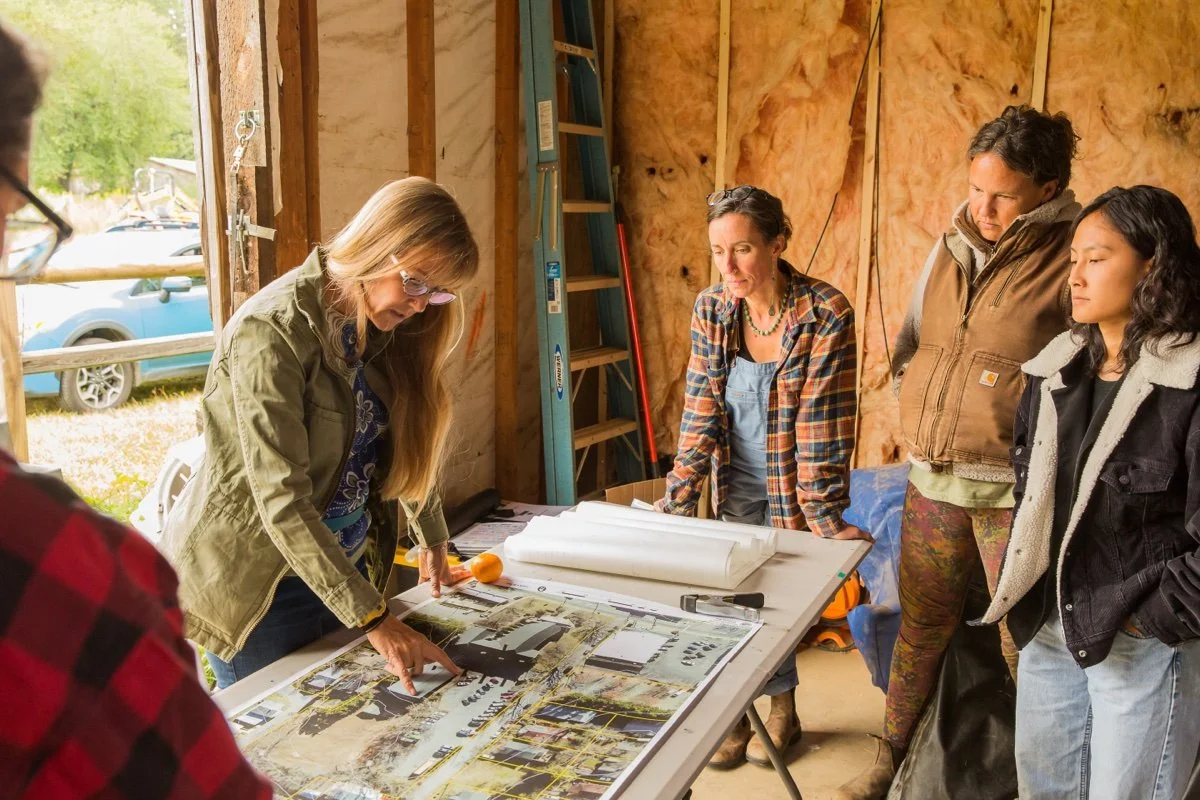 Group of people reviewing construction plans inside a building under construction.