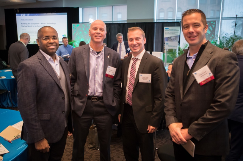 Phil Wilton standing and collaborating with three business professionals in a conference setting.