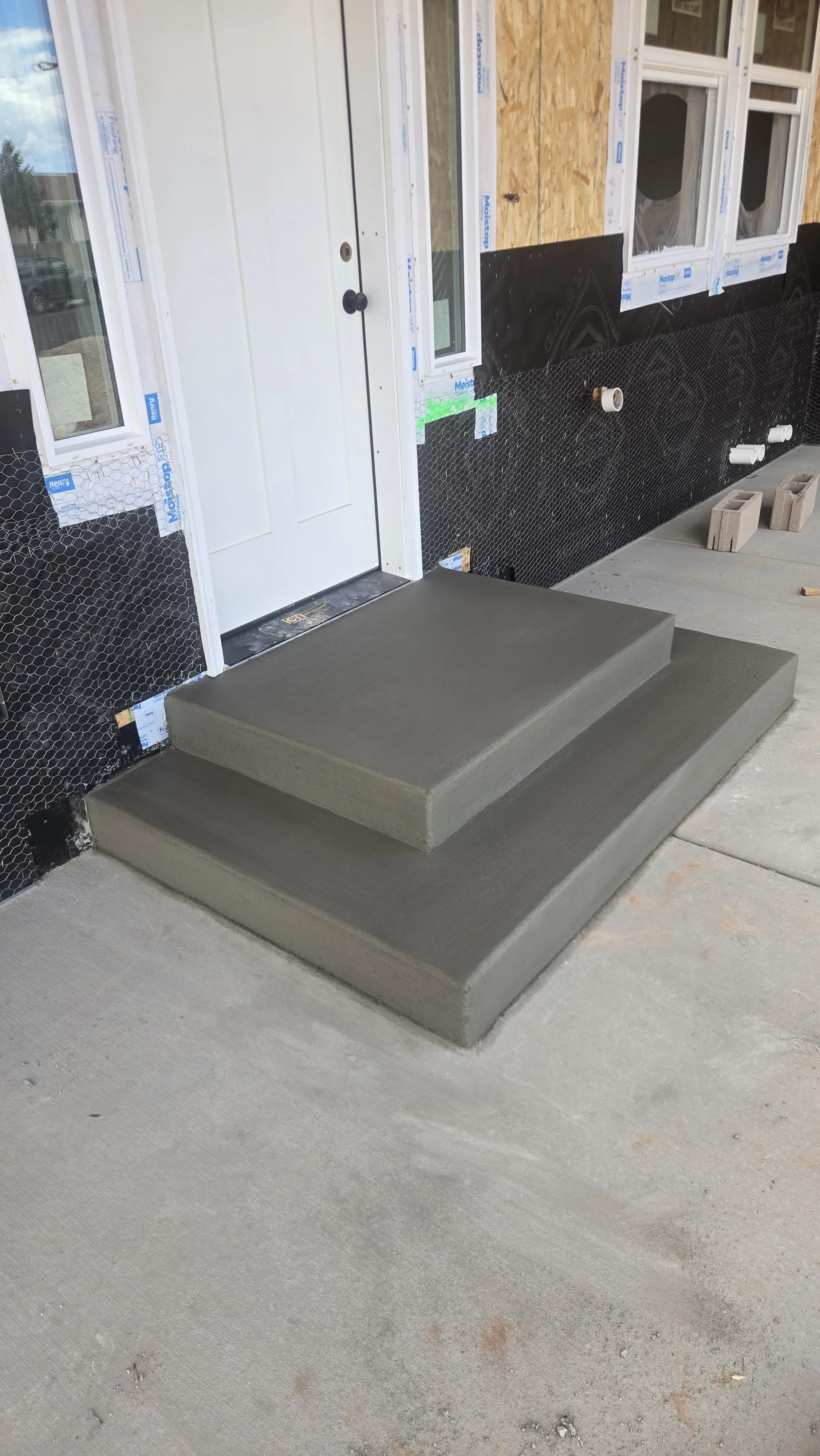 Concrete steps in front of a residential building under construction.