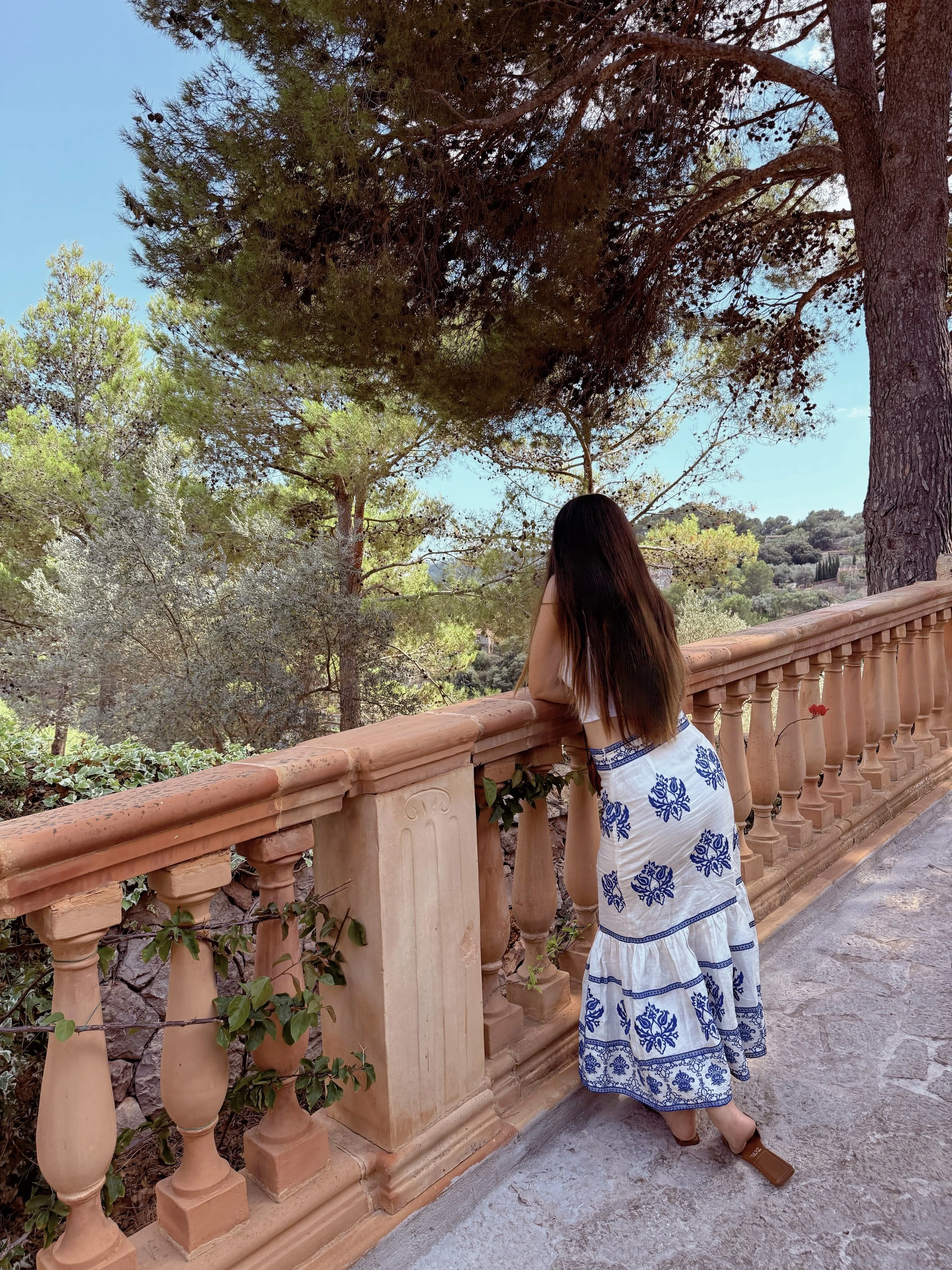 Woman with long hair gazing from a balcony in Mallorca across a verdant valley